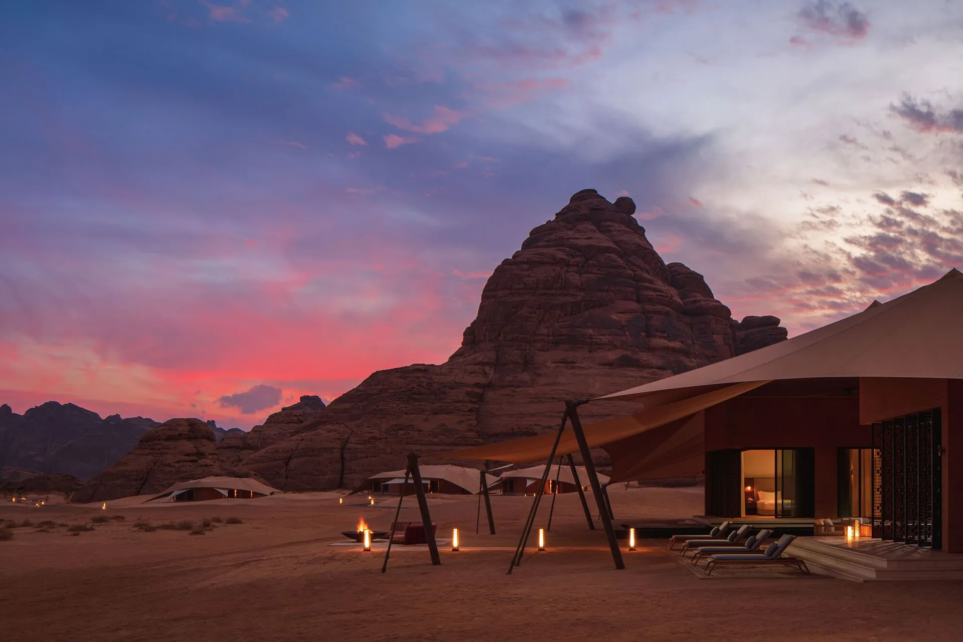 Desert landscape with a large rock formation in the background, set at sunset with warm colors and natural elements