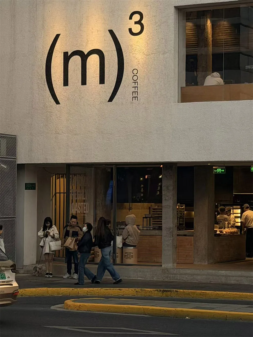 一間現代化的咖啡店，透過大窗戶，外面有群眾在城市環境中步行