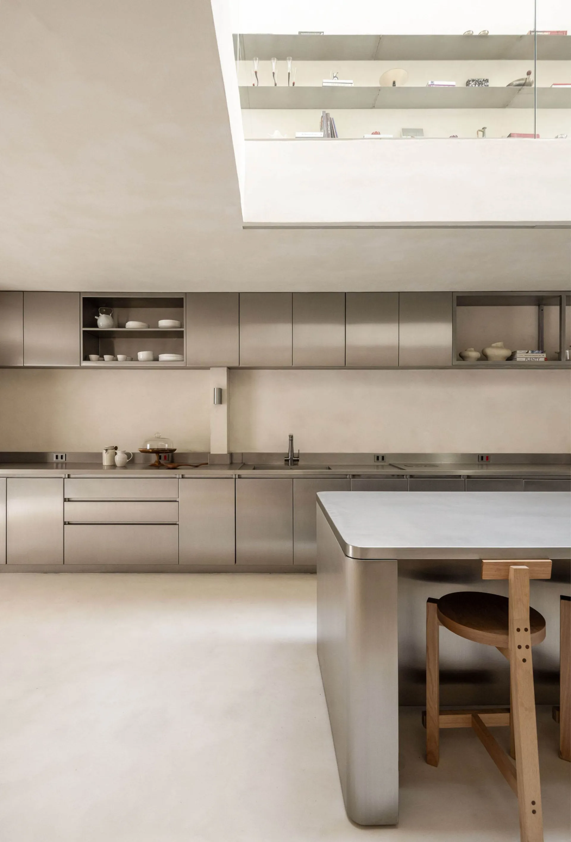 Modern kitchen with a stainless steel countertop and wooden table, featuring a sleek and inviting atmosphere with bright lighting