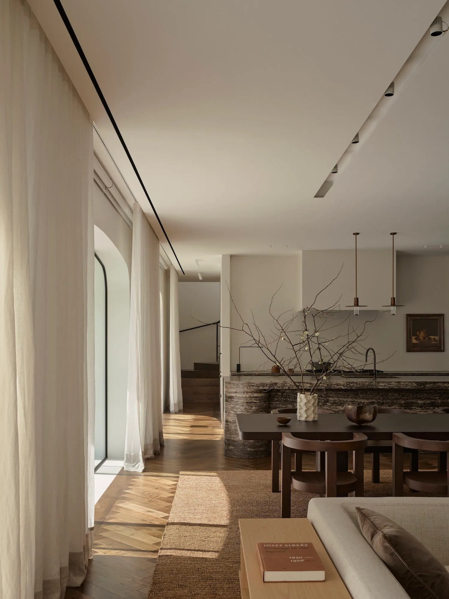 Well-lit modern kitchen with a wooden floor, stone countertop, and natural light from a window