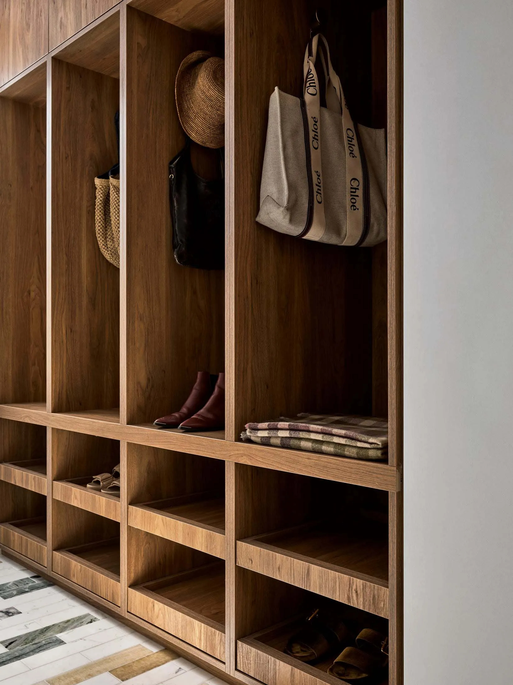 A storage room with wooden shelves filled with personal belongings, including a hat and a handbag, giving a warm and natural feel