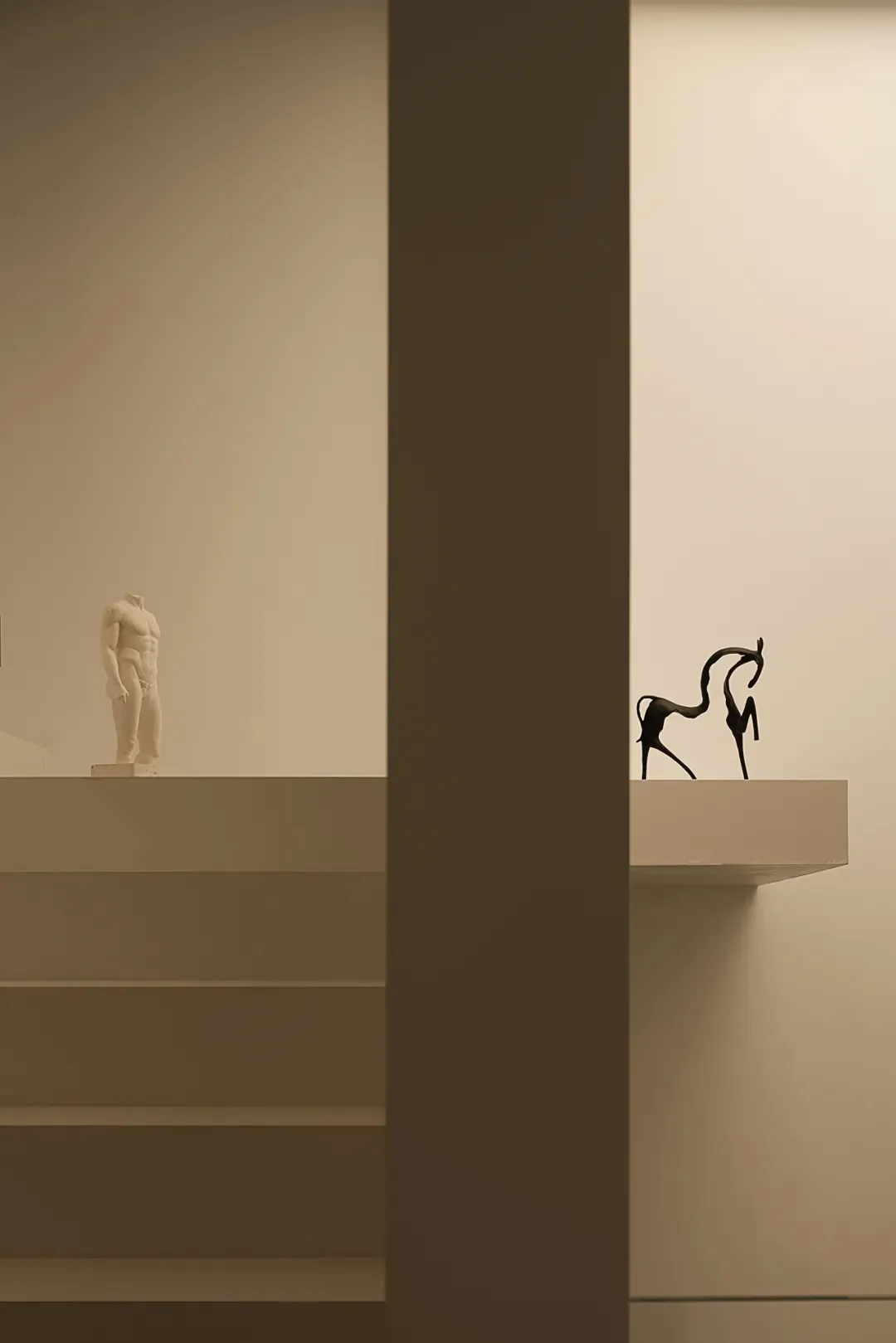 A dimly lit room with a statue on a pedestal in the center, surrounded by a museum or art gallery atmosphere