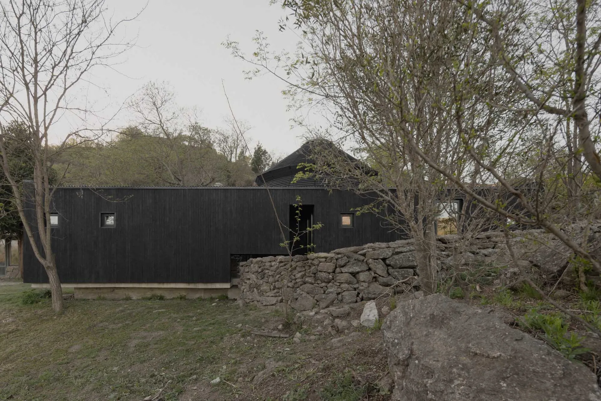 A small, traditional stone house with a black door and a simple design, captured in a black and white photograph from a low angle perspective