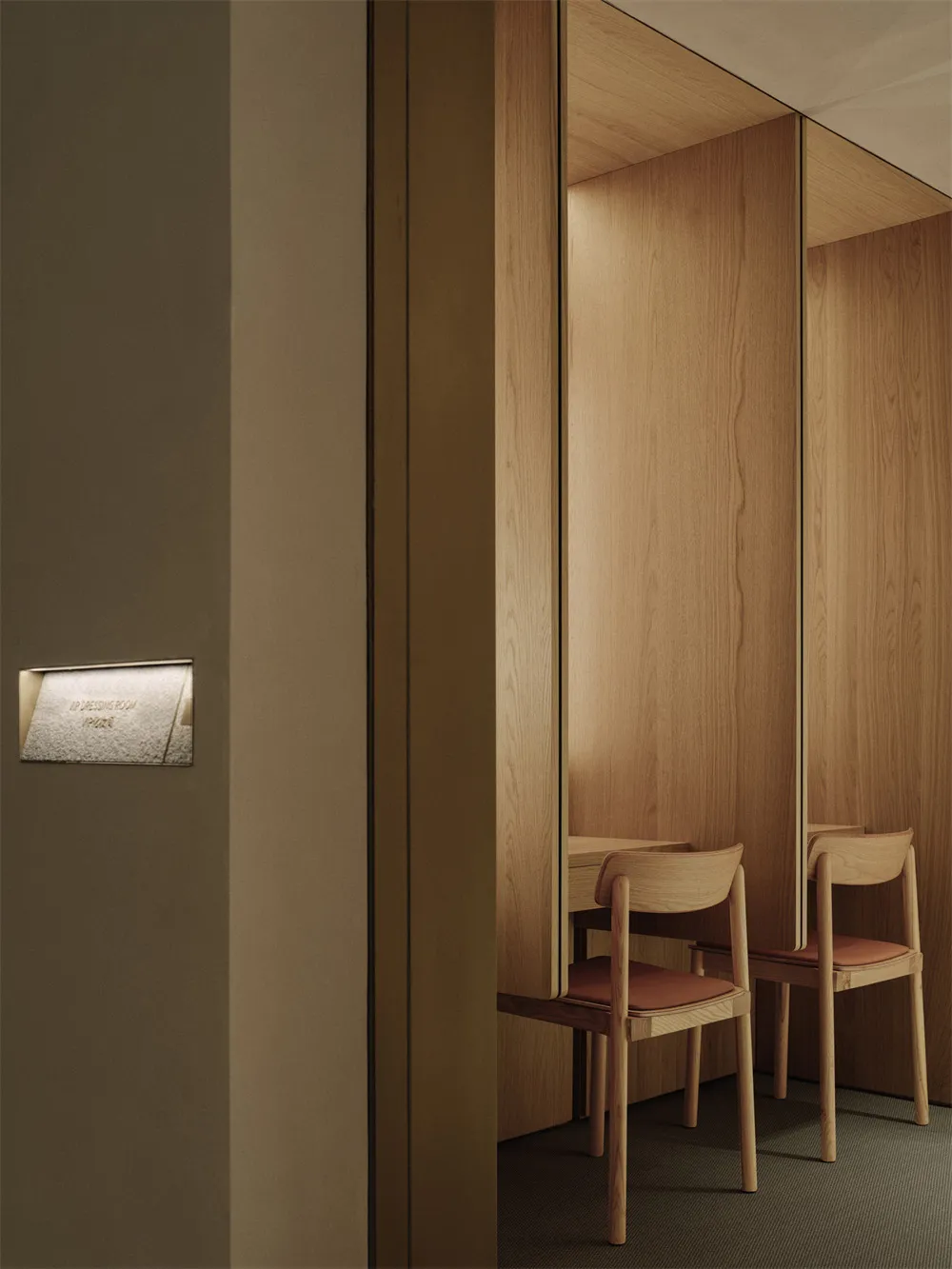 A bright and welcoming hallway with a doorway leading to a room with three wooden chairs and a wooden interior, illuminated by natural light