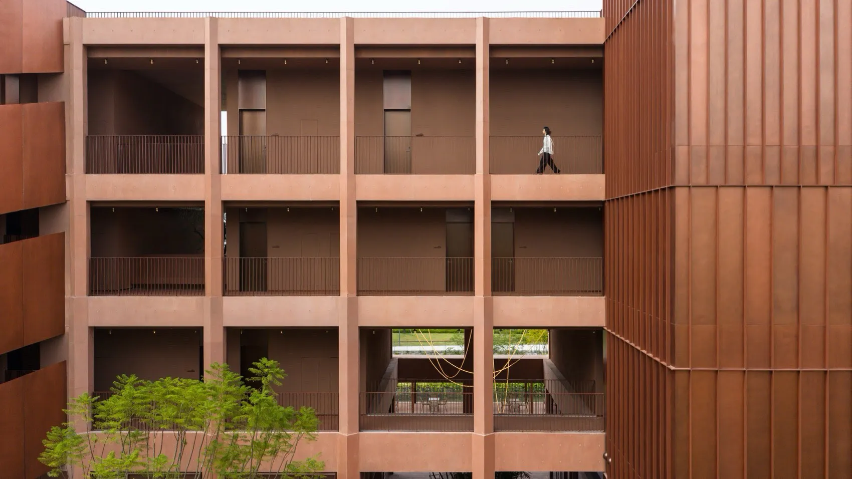 A dimly lit interior of a large building with a brown color scheme, featuring a woman walking down a hallway