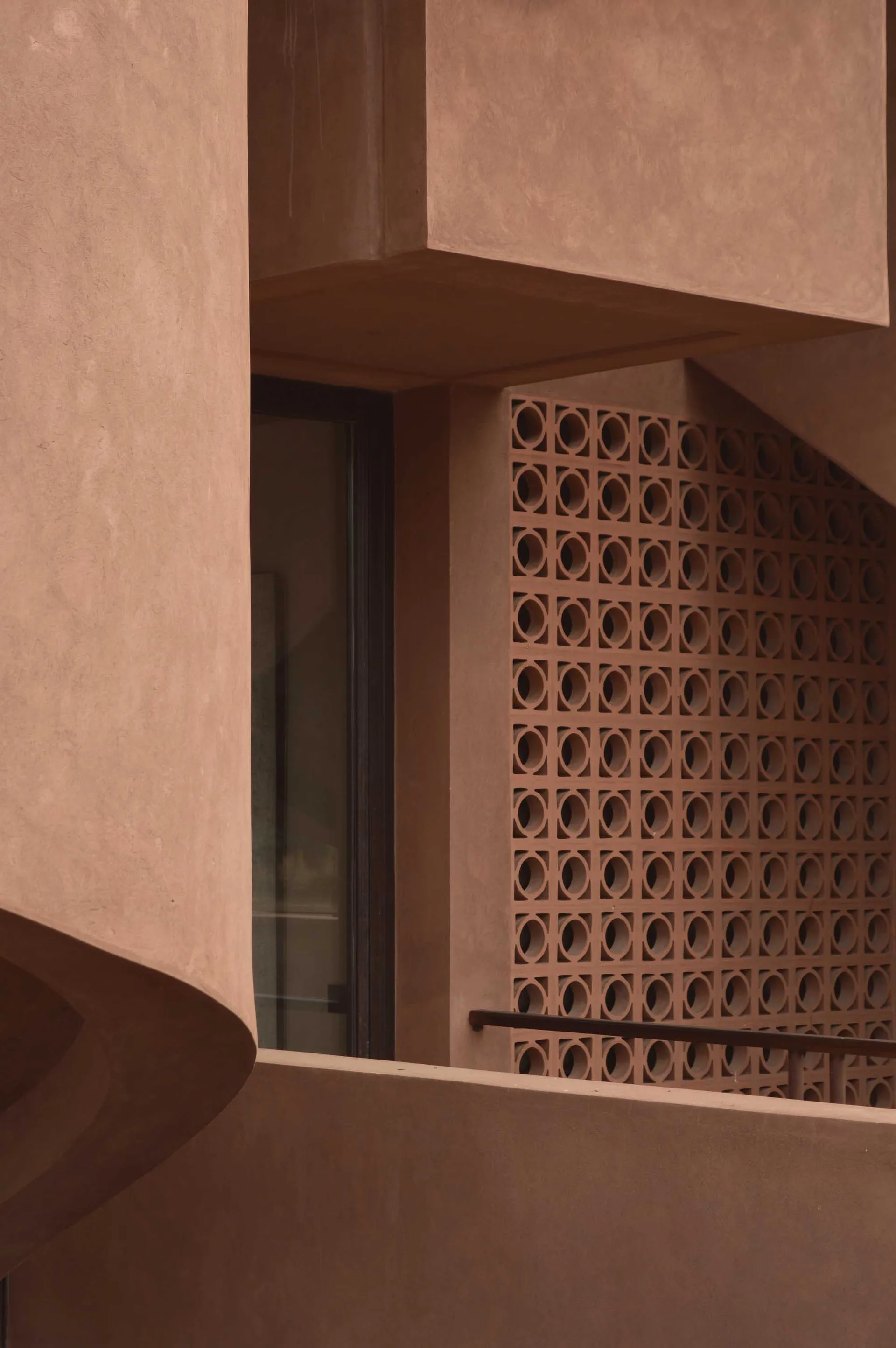 A brown building with a brick exterior, featuring a window with a view of a staircase, set in a natural outdoor environment with dark lighting