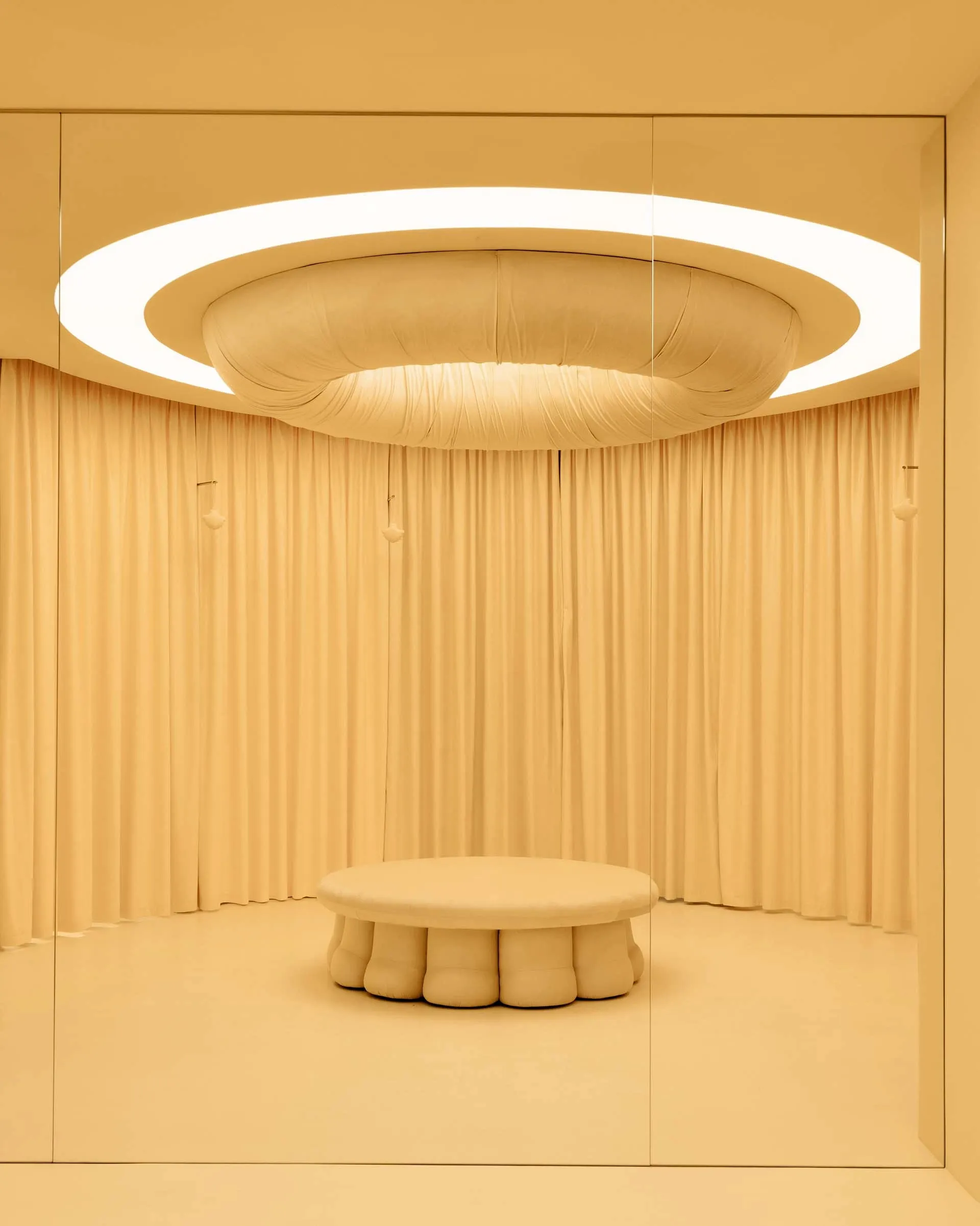 Bright and inviting dining space with a cream-colored fabric-covered wall, a large white circular table, and a warm atmosphere