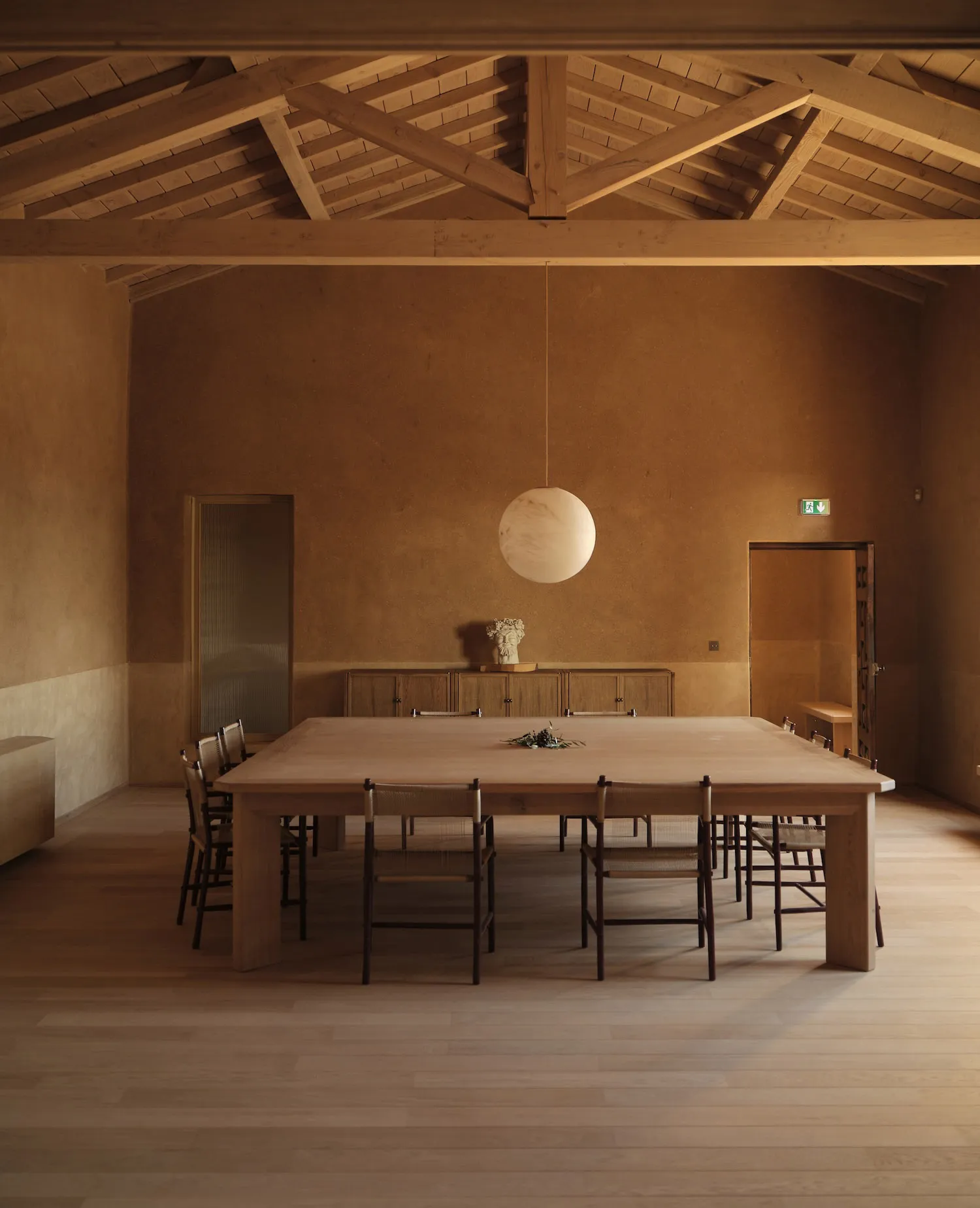 Warm dining space with a wooden table, chairs, and a potted plant, surrounded by wooden floor and inviting atmosphere