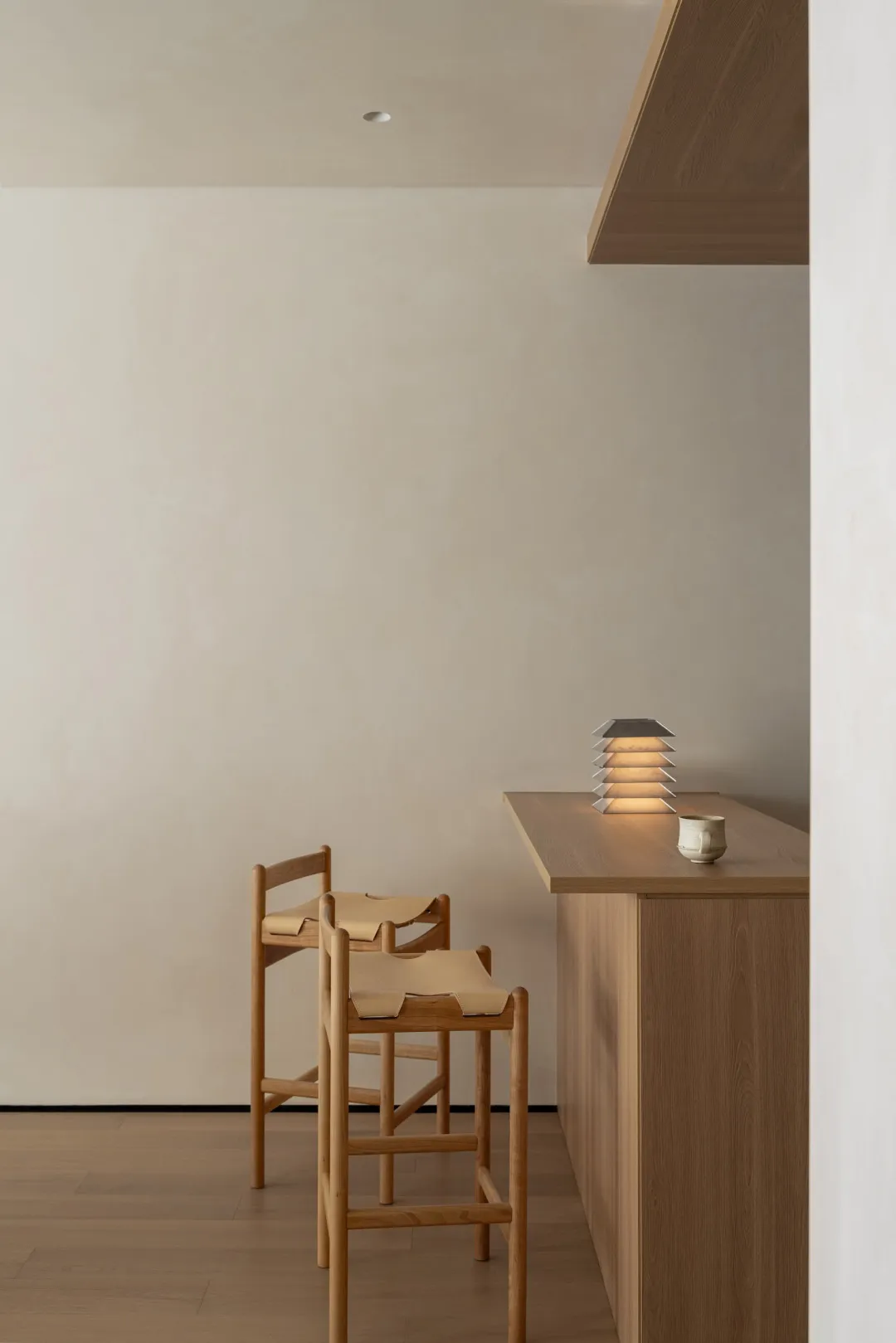 A kitchen or dining area with a wooden counter, chair, and overhead light, featuring a clean and organized space with a focus on functionality and simplicity