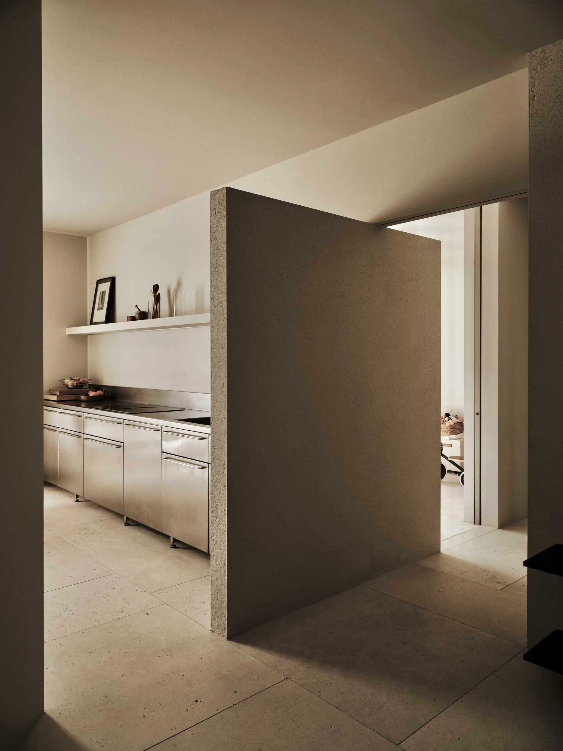 A modern kitchen with a white wall, marble countertop, stainless steel refrigerator, and dining table, lit dimly for a cozy atmosphere