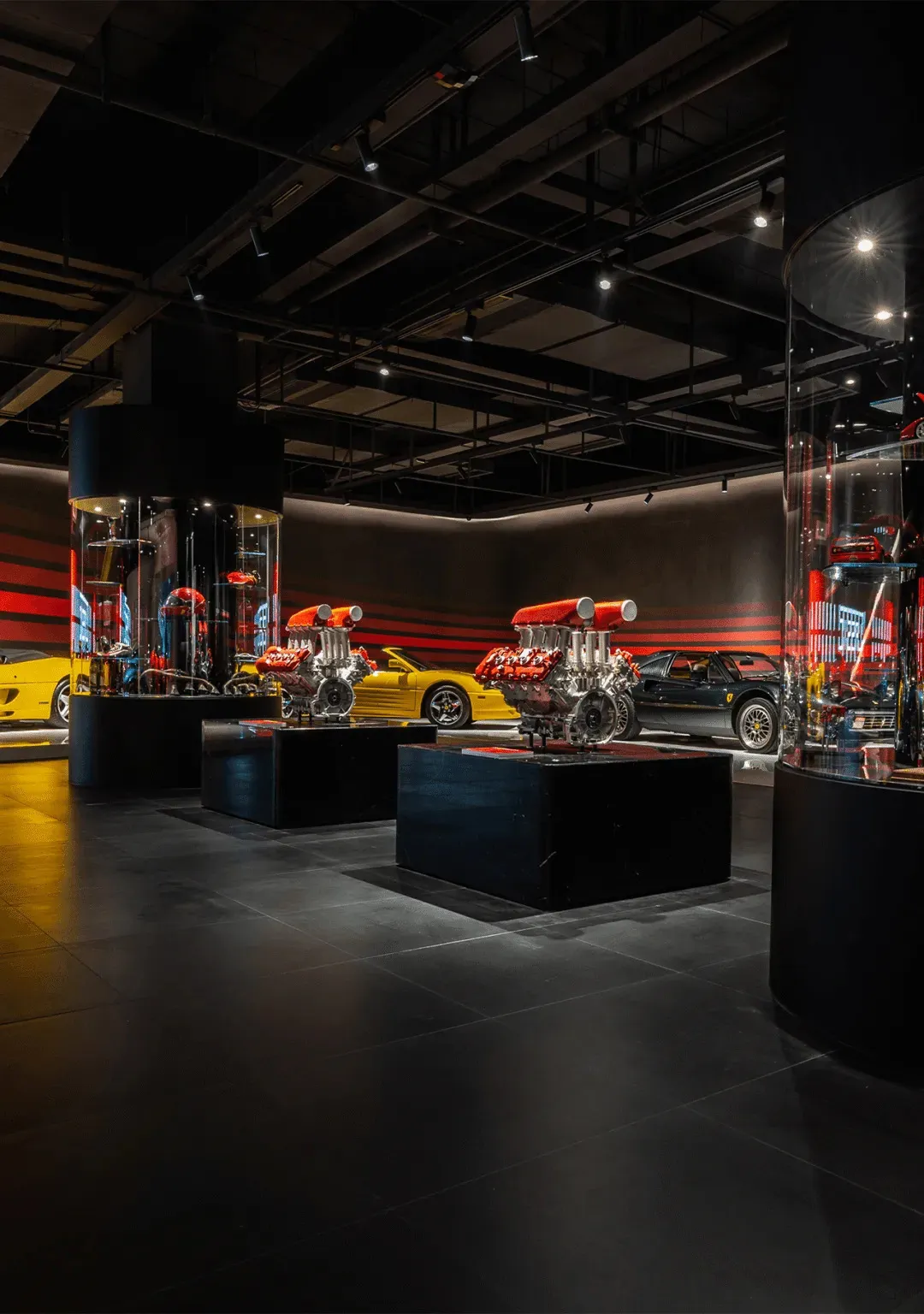 A modern sports car showroom with various cars on display on black carpet and concrete floor, well-lit and inviting