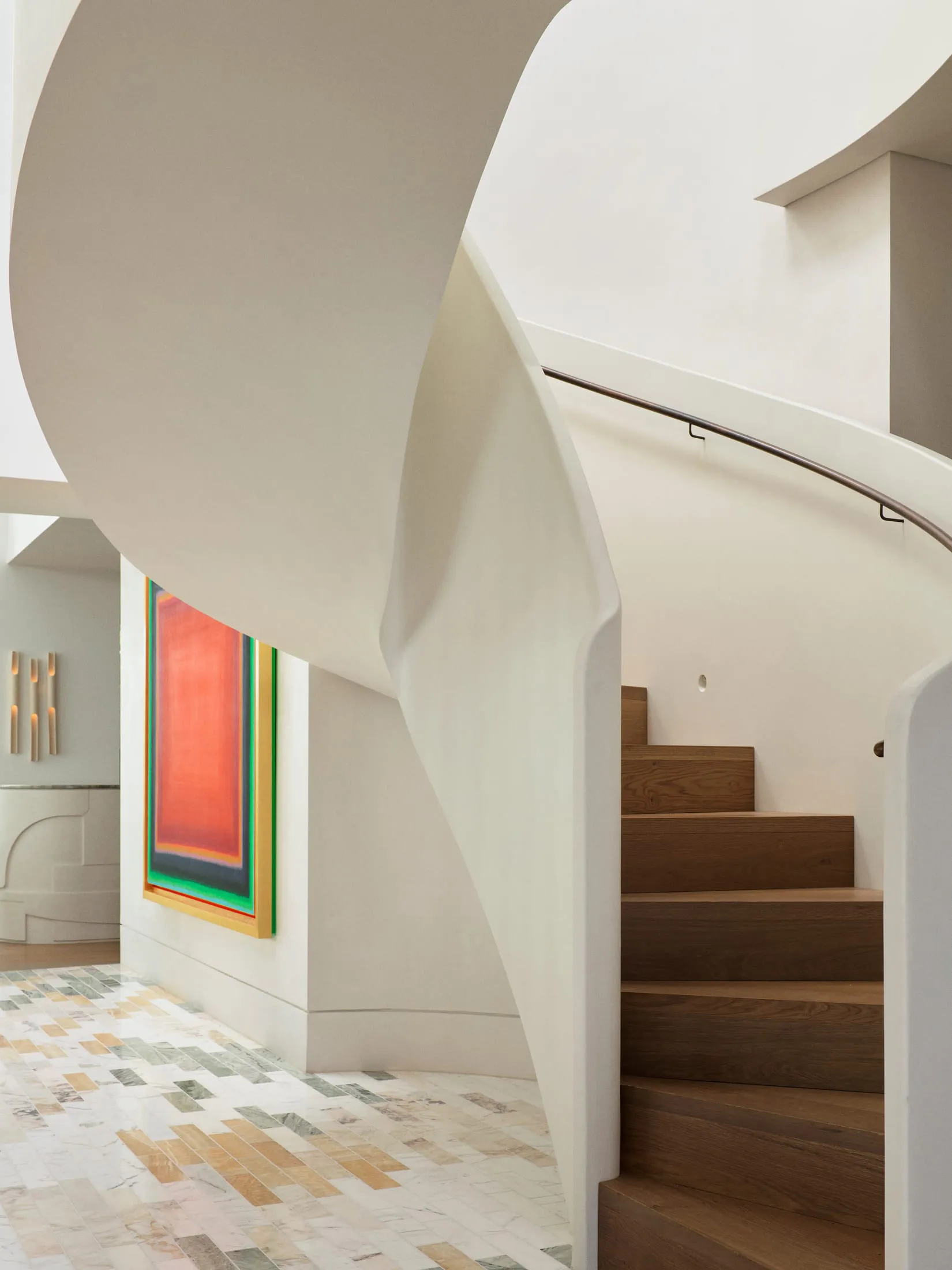 A modern staircase with white and wooden steps in a residential hallway, lit by natural sunlight from a window