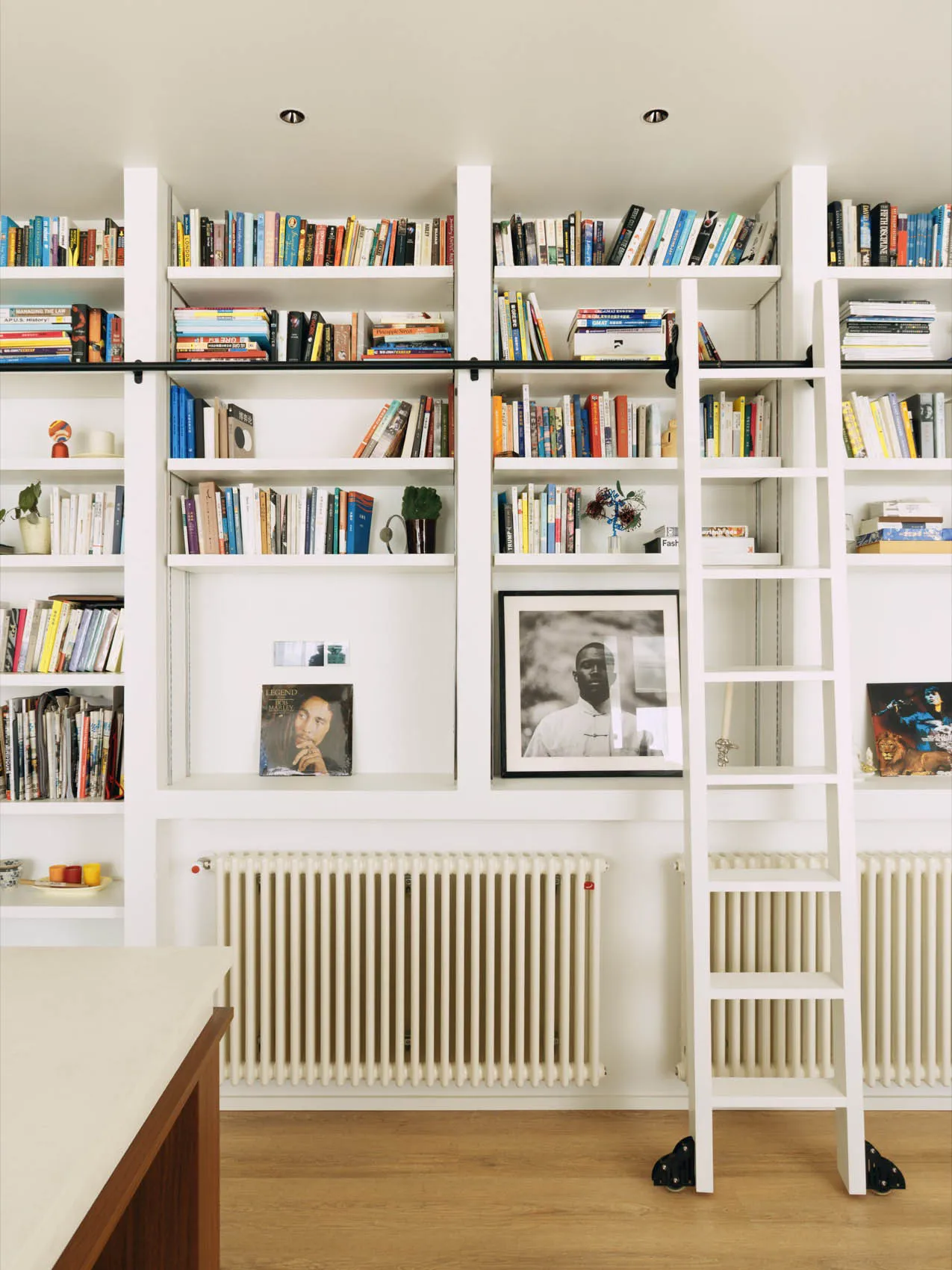 A calm and organized study area with a white bookshelf in the center, filled with books of various sizes and colors