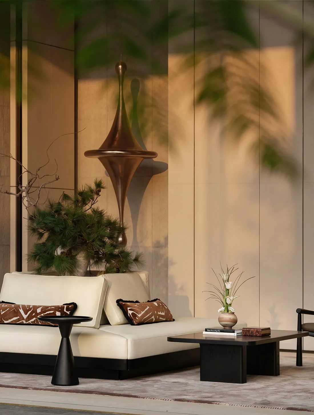 A well-lit living room with a white couch and chair on a hardwood floor, featuring a potted plant and a comfortable atmosphere