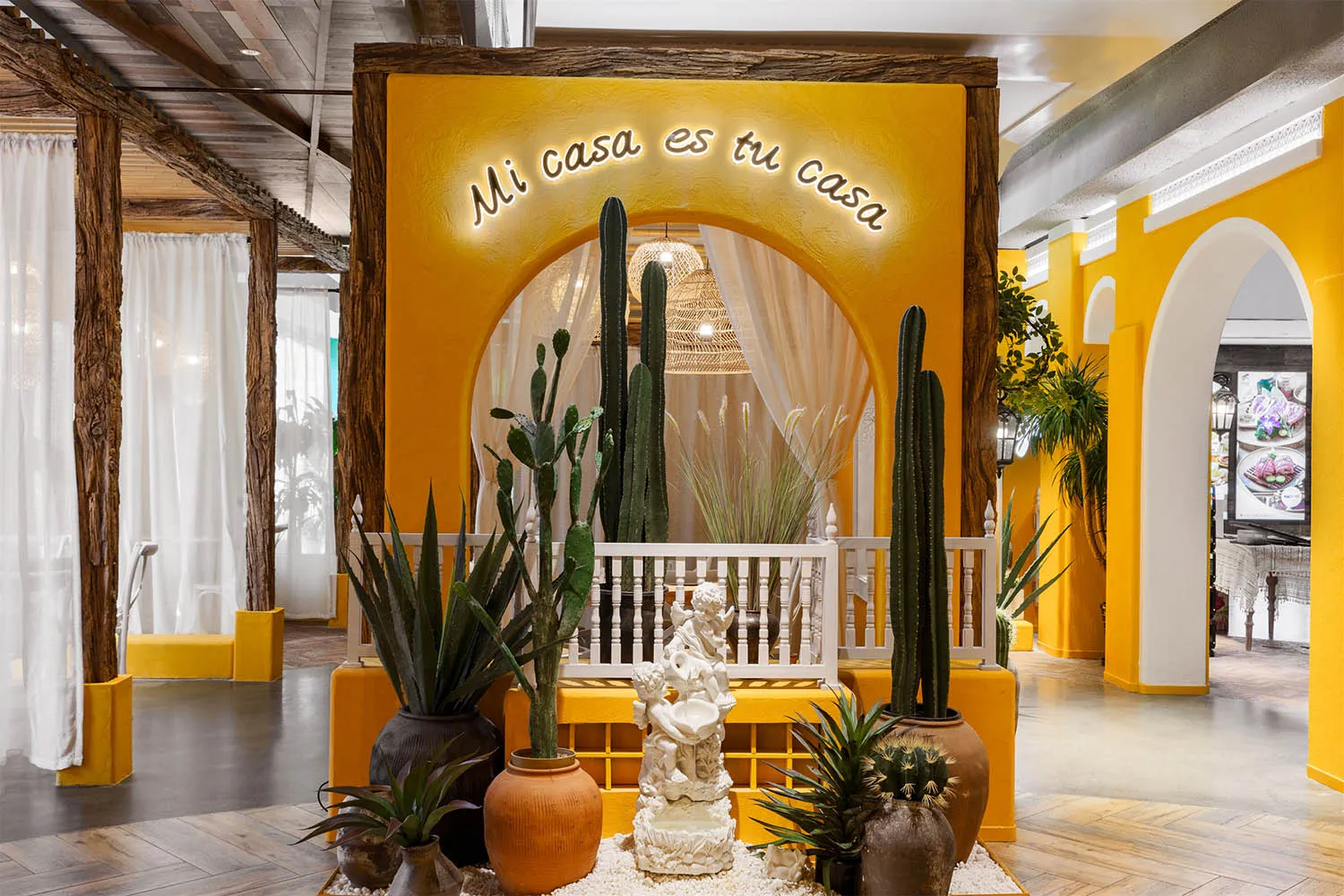 A room with a yellow wall, a white bench, and potted plants, including cacti, surrounded by decorative vases, with soft and warm lighting creating a cozy atmosphere