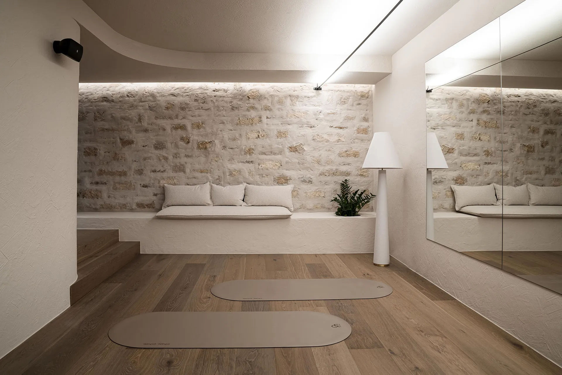 Comfortable living space with a stone wall, a couch, a chair, and a potted plant, well-lit and inviting