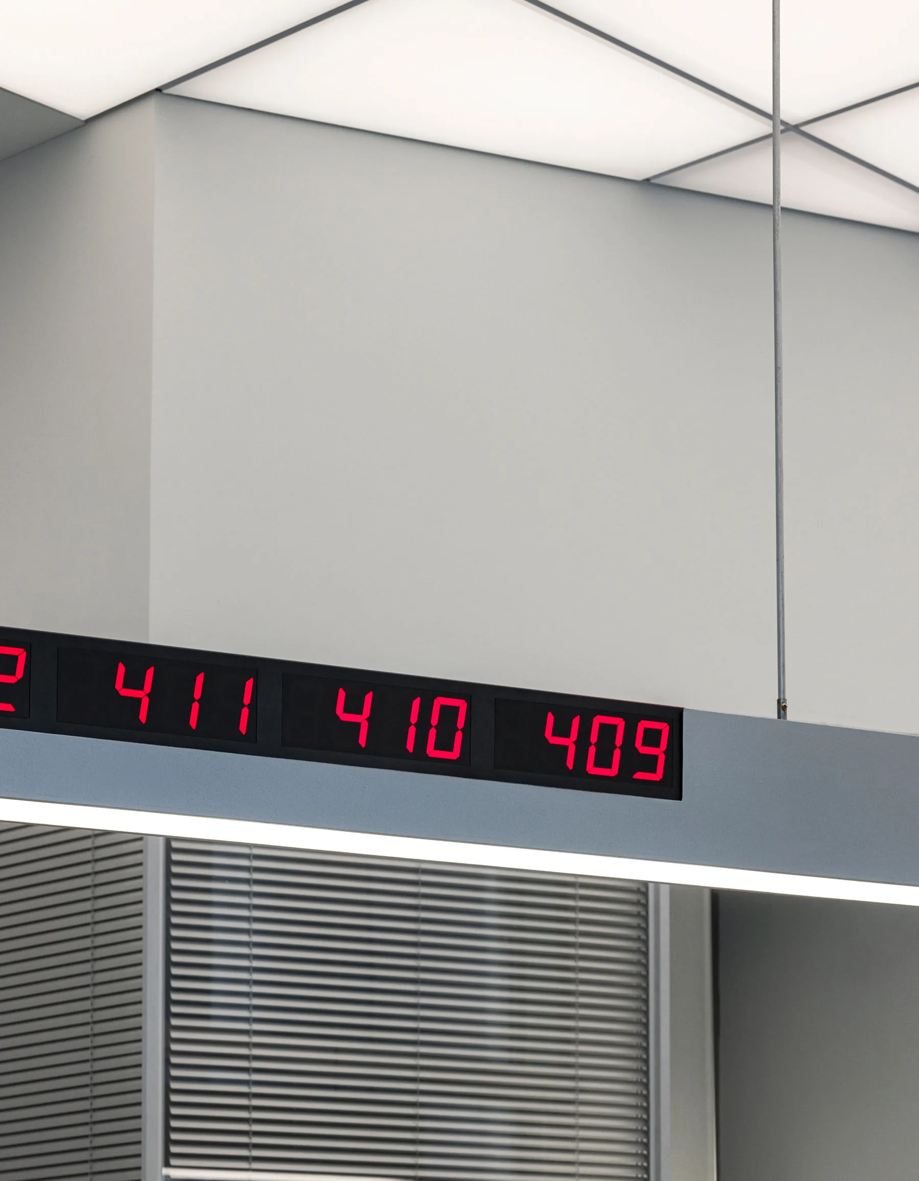 A minimalist room with a white color scheme, a digital clock mounted on the wall, and a sparse, empty space