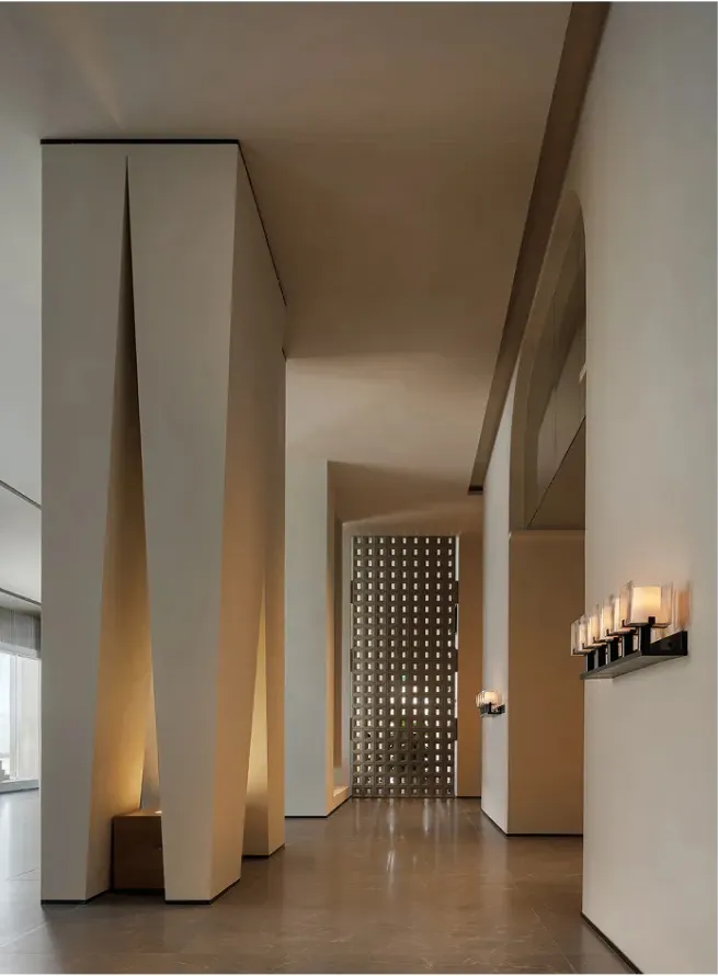 A long and narrow hallway with a white color scheme, patterned walls, and dim lighting, lined with series of lights