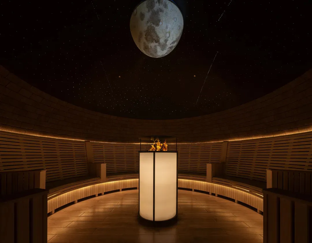 A dimly lit, modern lobby with a large white pillar as the focal point, surrounded by empty space and a predominantly white color scheme