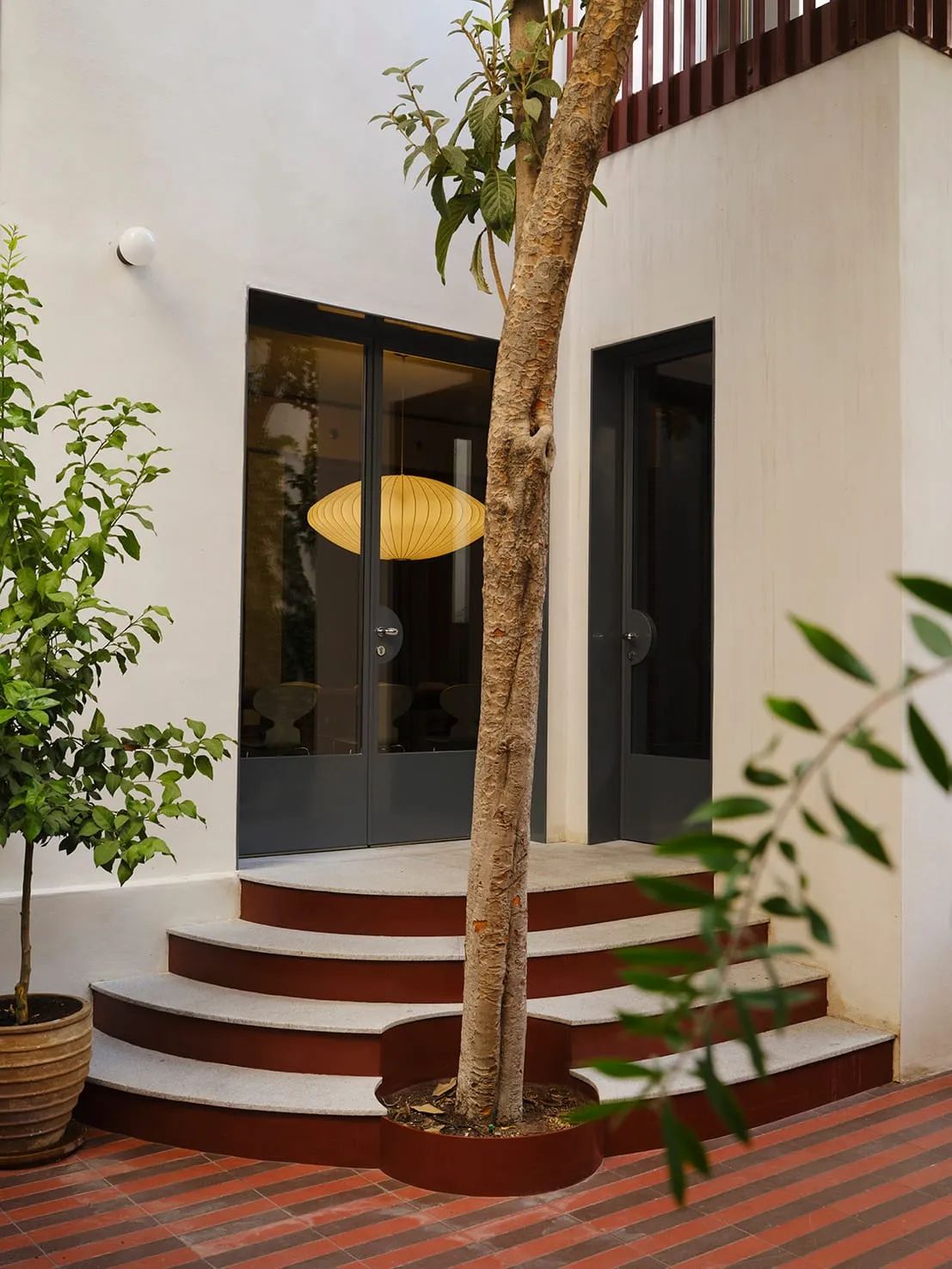 A modern house with a wooden staircase and concrete exterior, set in a natural outdoor setting with a calm and inviting atmosphere