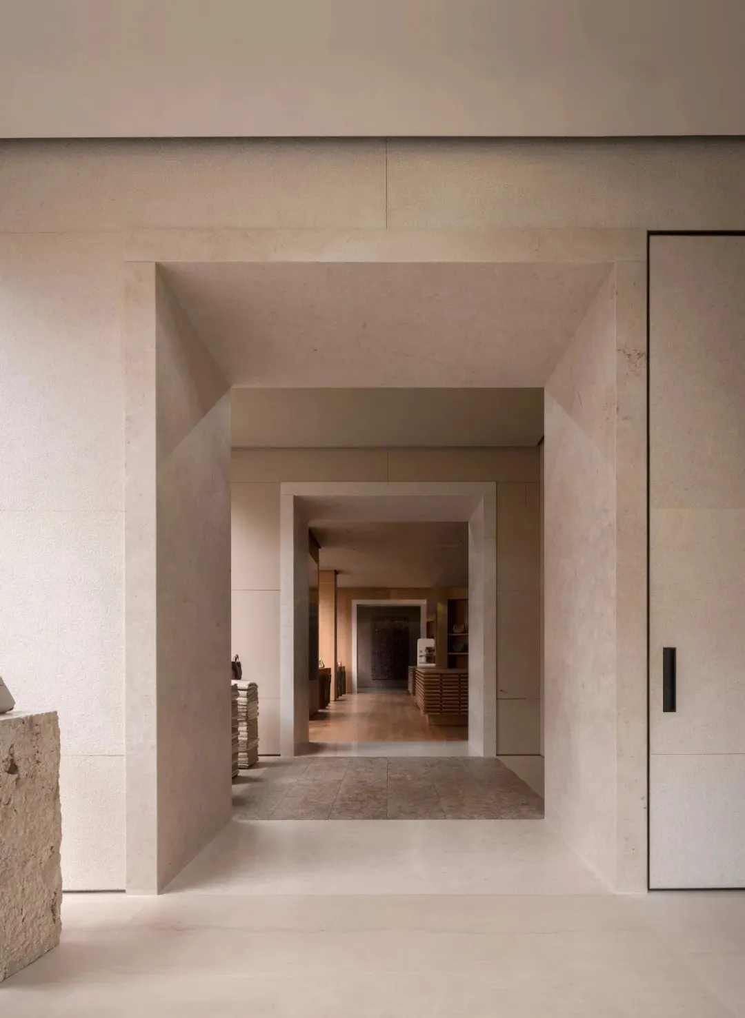 Narrow hallway with white marble floor, white walls, and dim lighting, featuring books on the floor