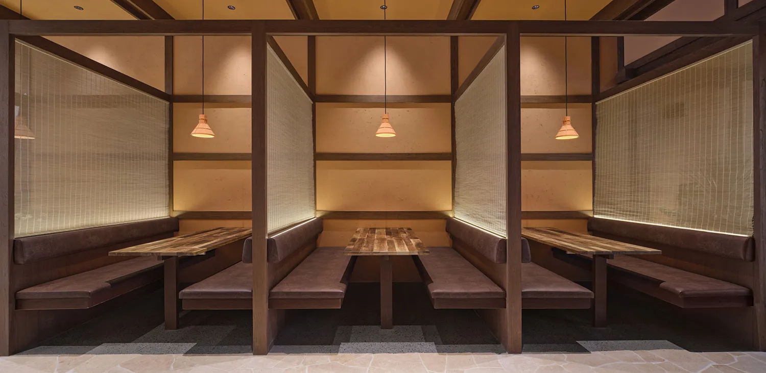 木質餐廳區域的餐桌、木質長椅和舒適枕頭，點亮了一系列燈光