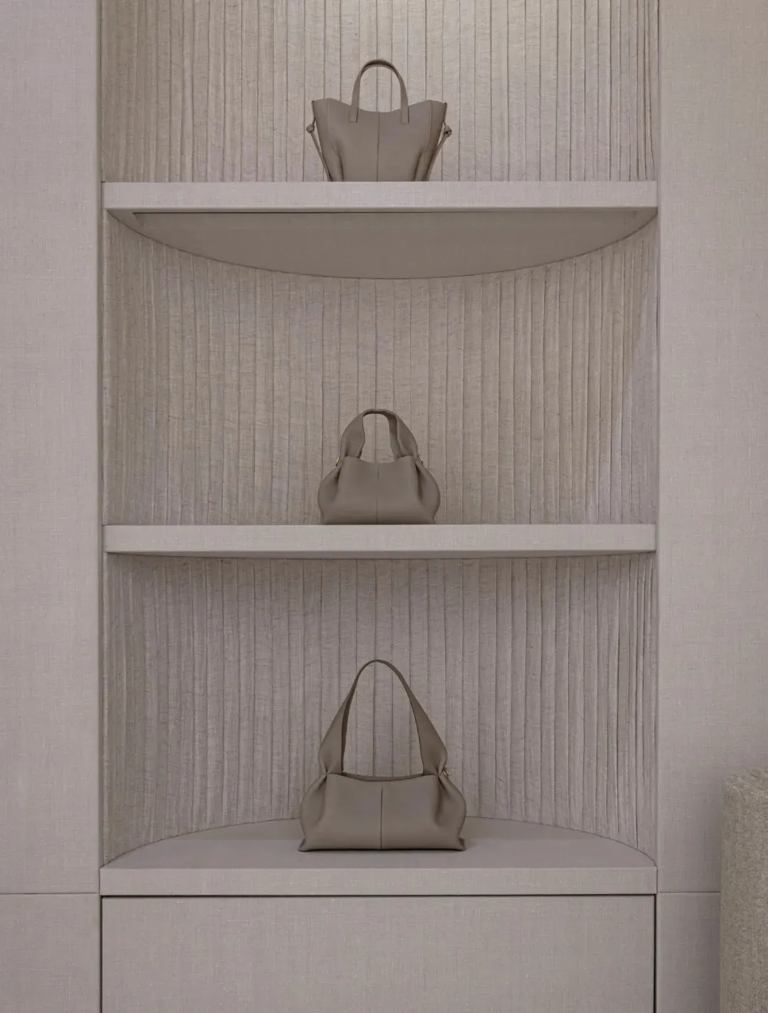 A display case made of wood holds a variety of colorful handbags arranged neatly on shelves in an elegant and sophisticated manner