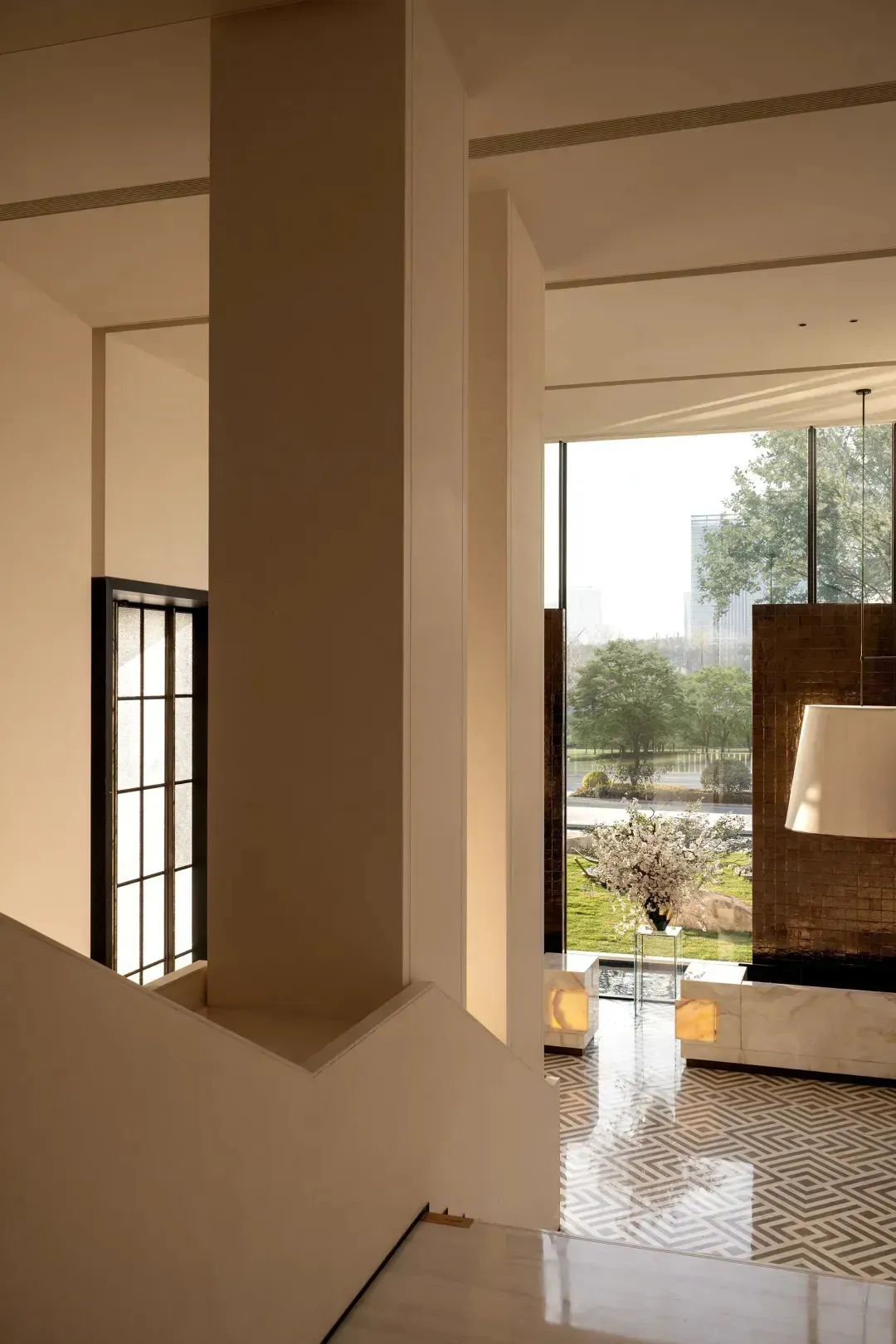 A well-lit living room with a stone staircase, white walls, a couch, chair, and potted plant, creating a welcoming atmosphere