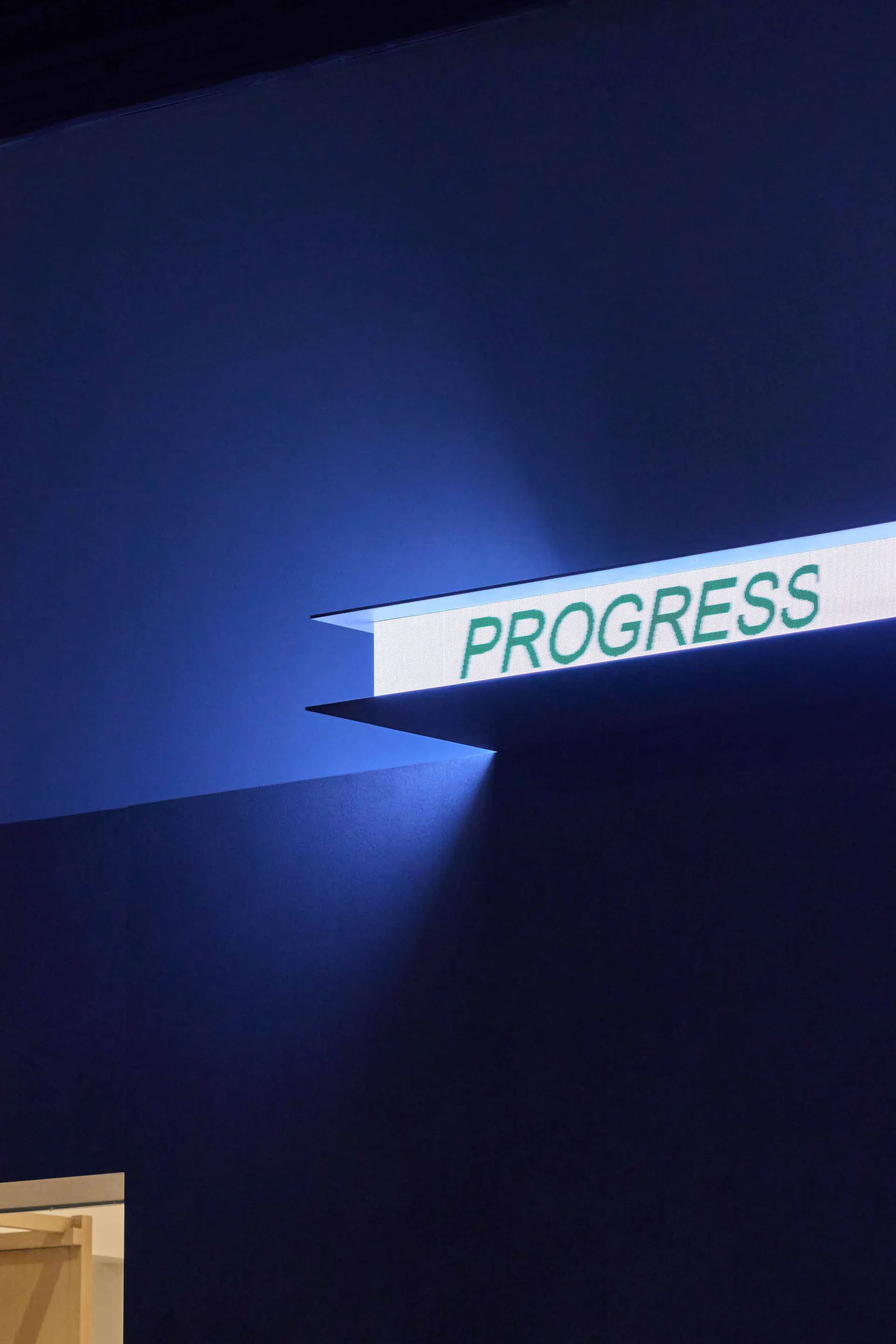 A blue-lit sign reading Progress mounted on a wall, giving a futuristic appearance
