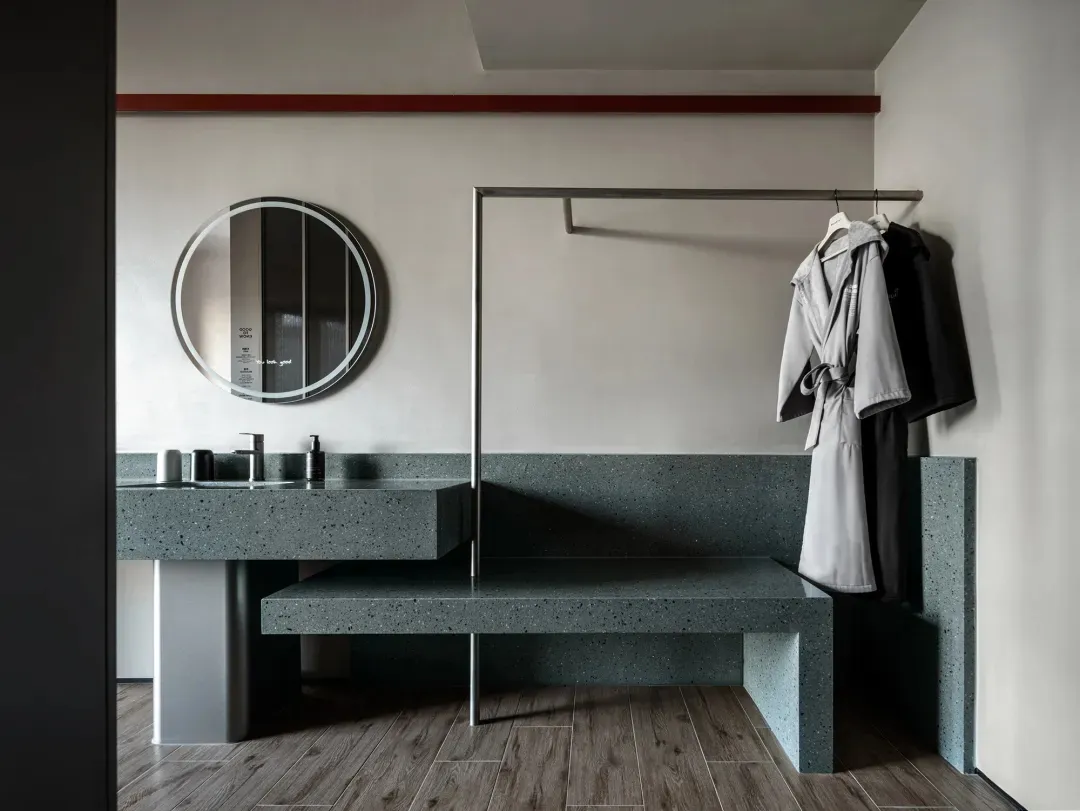 Modern bathroom with a stone bench, mirror, and coat rack, well-lit with clean lines and functionality