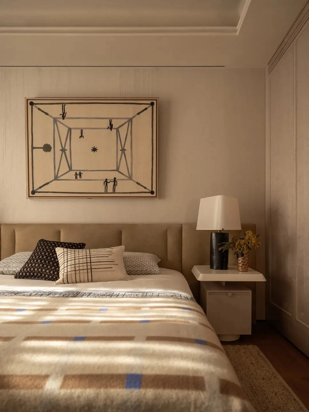 A cozy bedroom with a bed, lamp, and painting, featuring a modern style with wood and fabric materials, and natural lighting