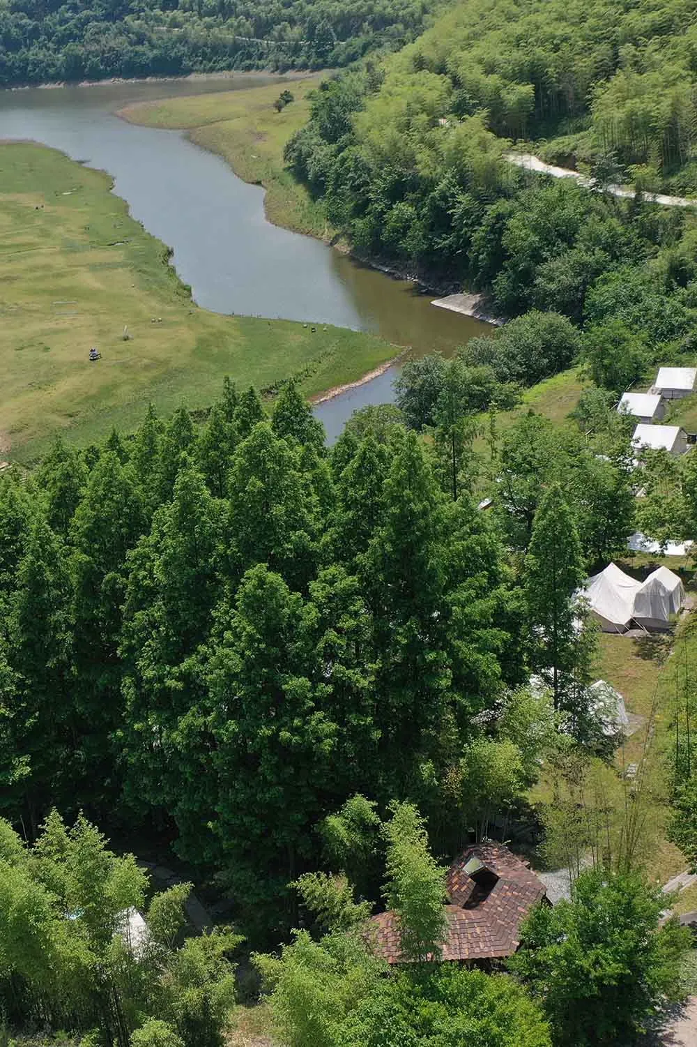 A serene riverfront scene with a wooden house, surrounded by trees and natural elements, with sunlight streaming through the trees