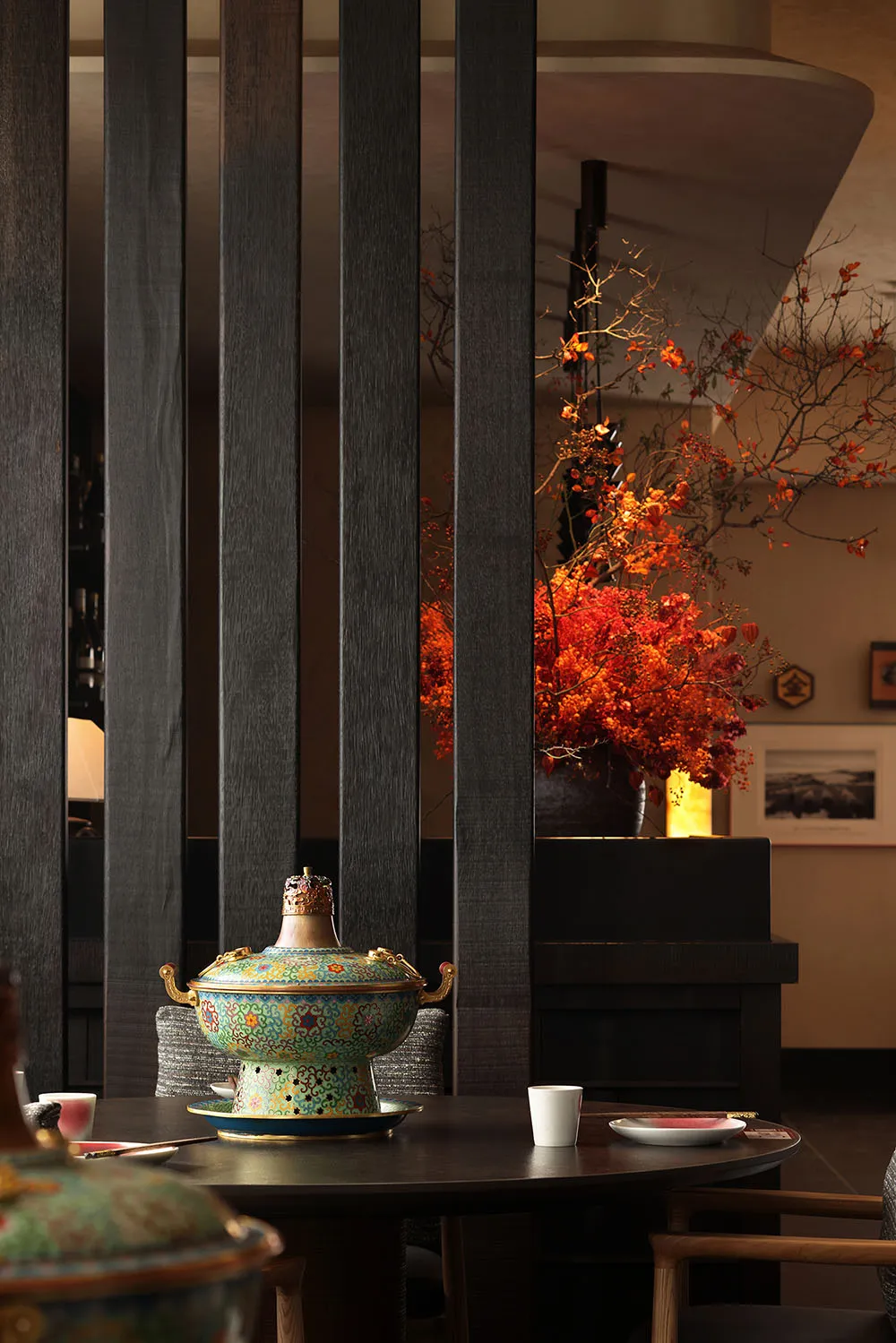 Dimly lit modern dining space with a black and white color scheme, a dining table, chair, couch, and potted plant, with a cozy and intimate atmosphere