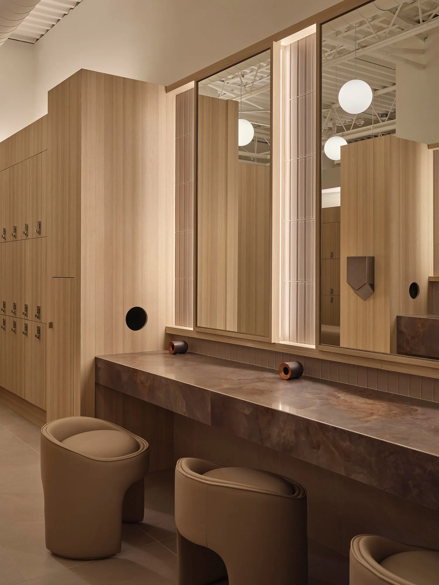 Bathroom with wooden walls, a wooden bench, and a large mirror reflecting the sink and interior