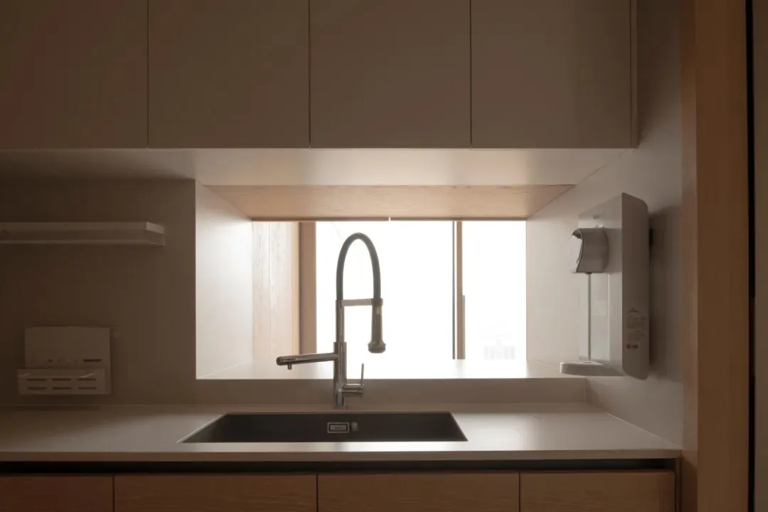 A well-lit kitchen with a metal sink and window, allowing natural light to enter and creating a pleasant atmosphere