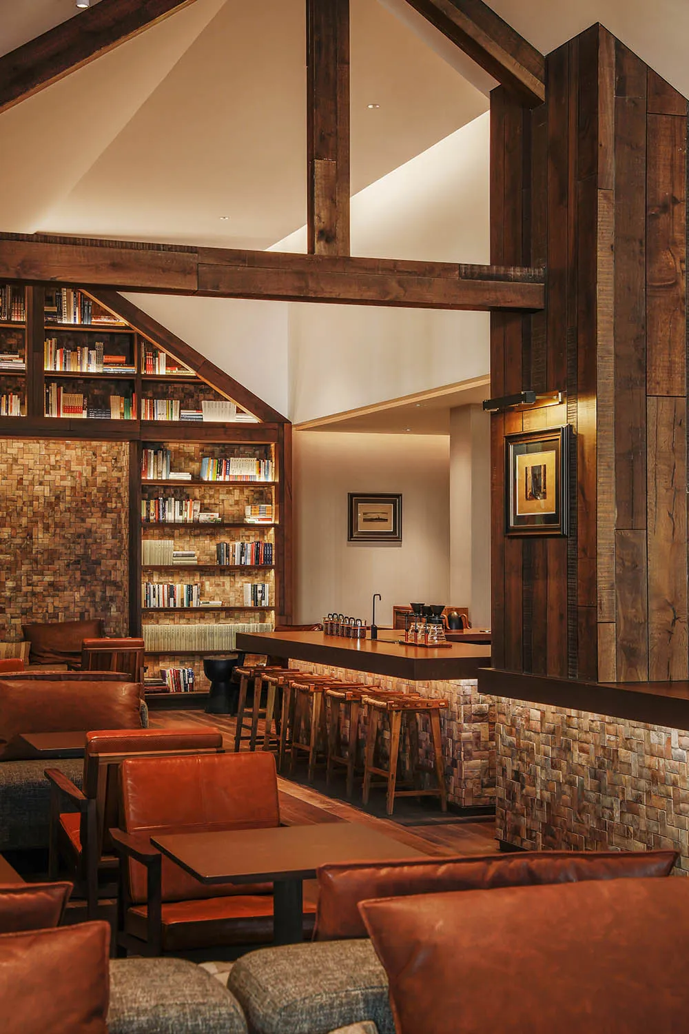 Cozy living room with a brick wall, wooden floor, and comfortable furniture, including a dining table, couch, and bookshelf, creating a warm and inviting atmosphere