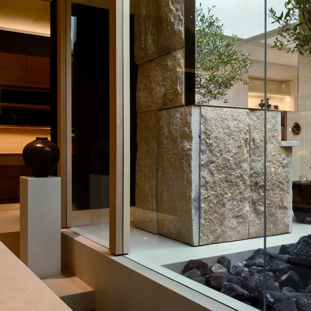Cozy living room with a rock wall, glass wall, and fireplace, featuring a modern style with natural elements and dim lighting