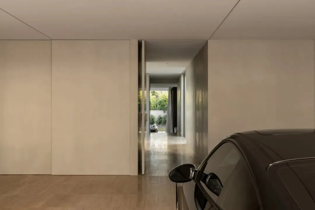A calm and inviting living room with a white color scheme, natural light, and a doorway leading to a hallway and garage