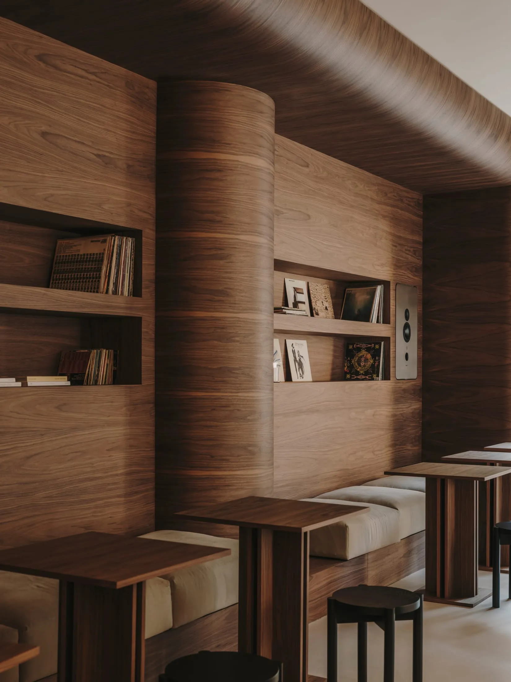 A warm and cozy restaurant with wooden walls and a wooden table, featuring books and a reading area