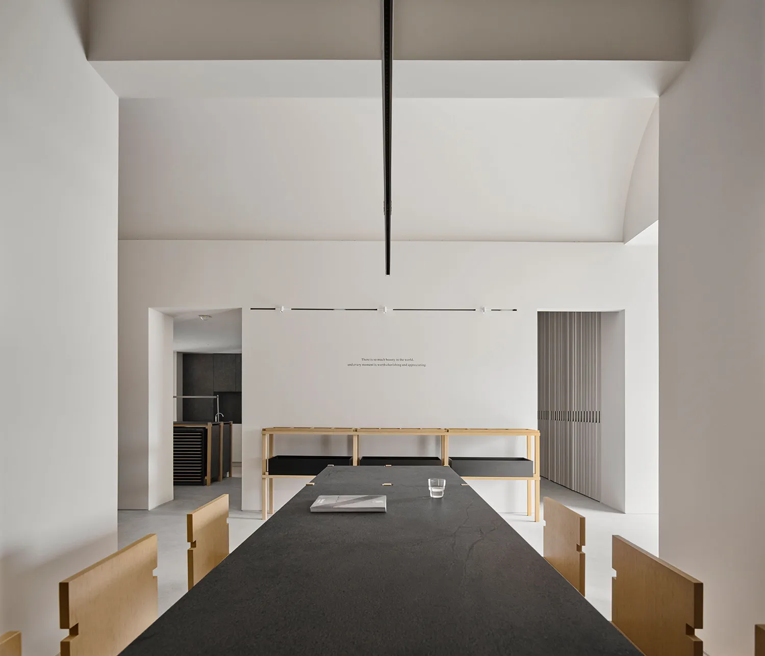 A large, open dining room with a modern design, white walls, and soft lighting, featuring a dining table and chairs, and a vase on the table