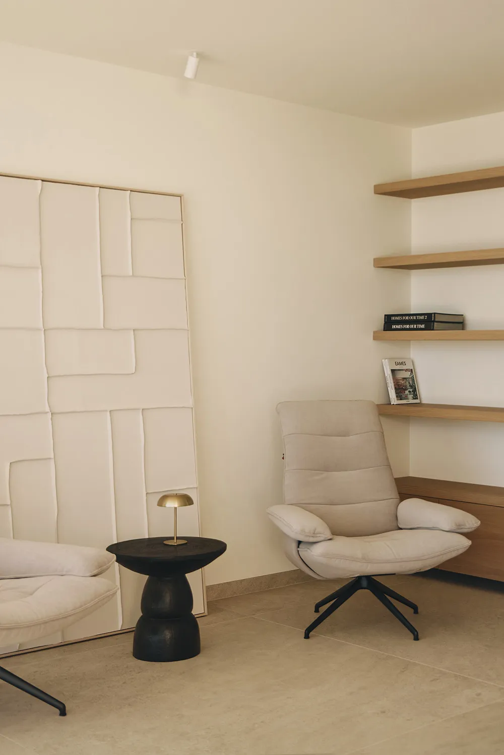 Cozy living space with a white chair, couch, and bookshelf, surrounded by natural light from a window