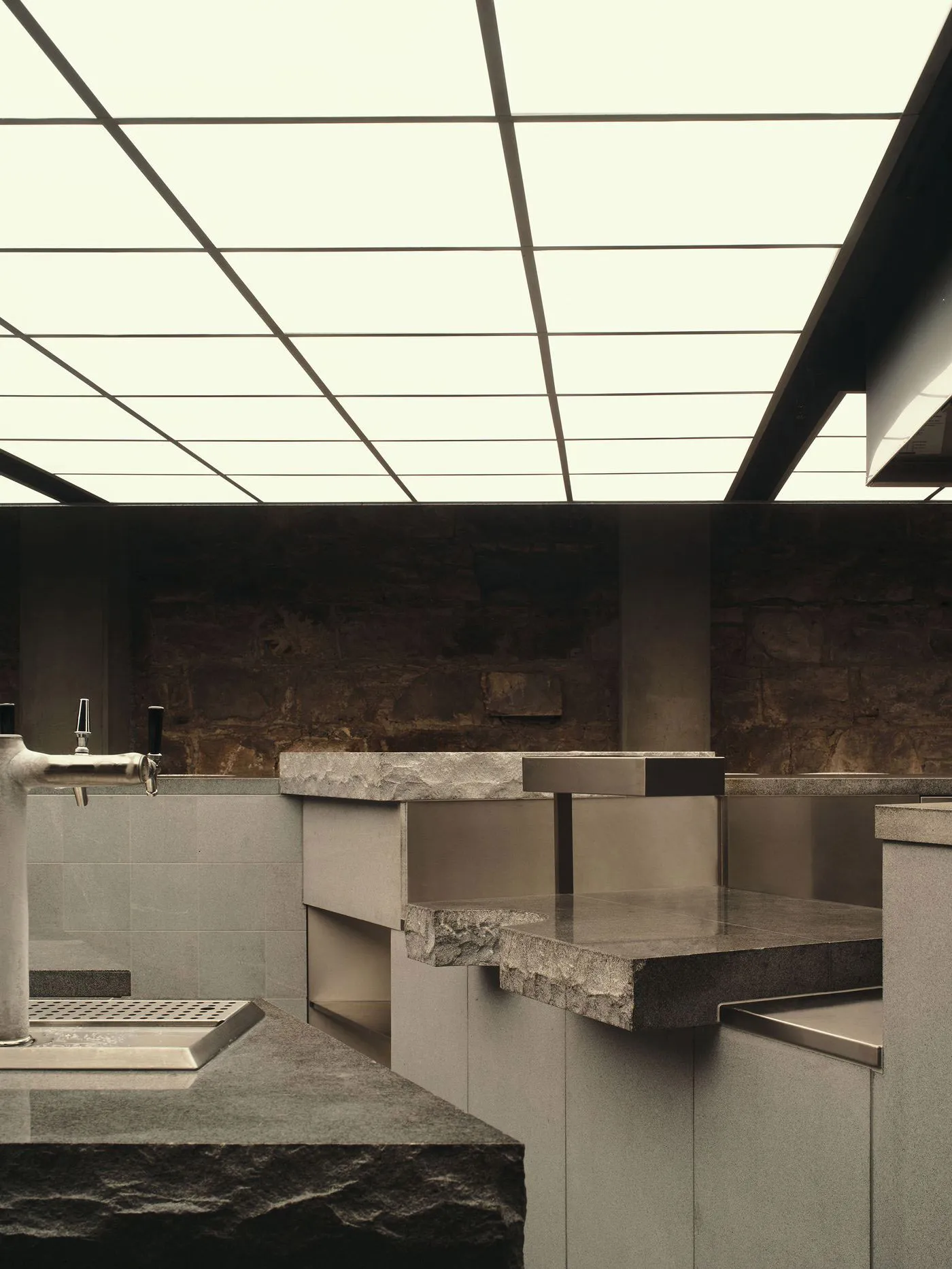 Bathroom with a stone countertop, sink, and shower in a modern style with dim lighting
