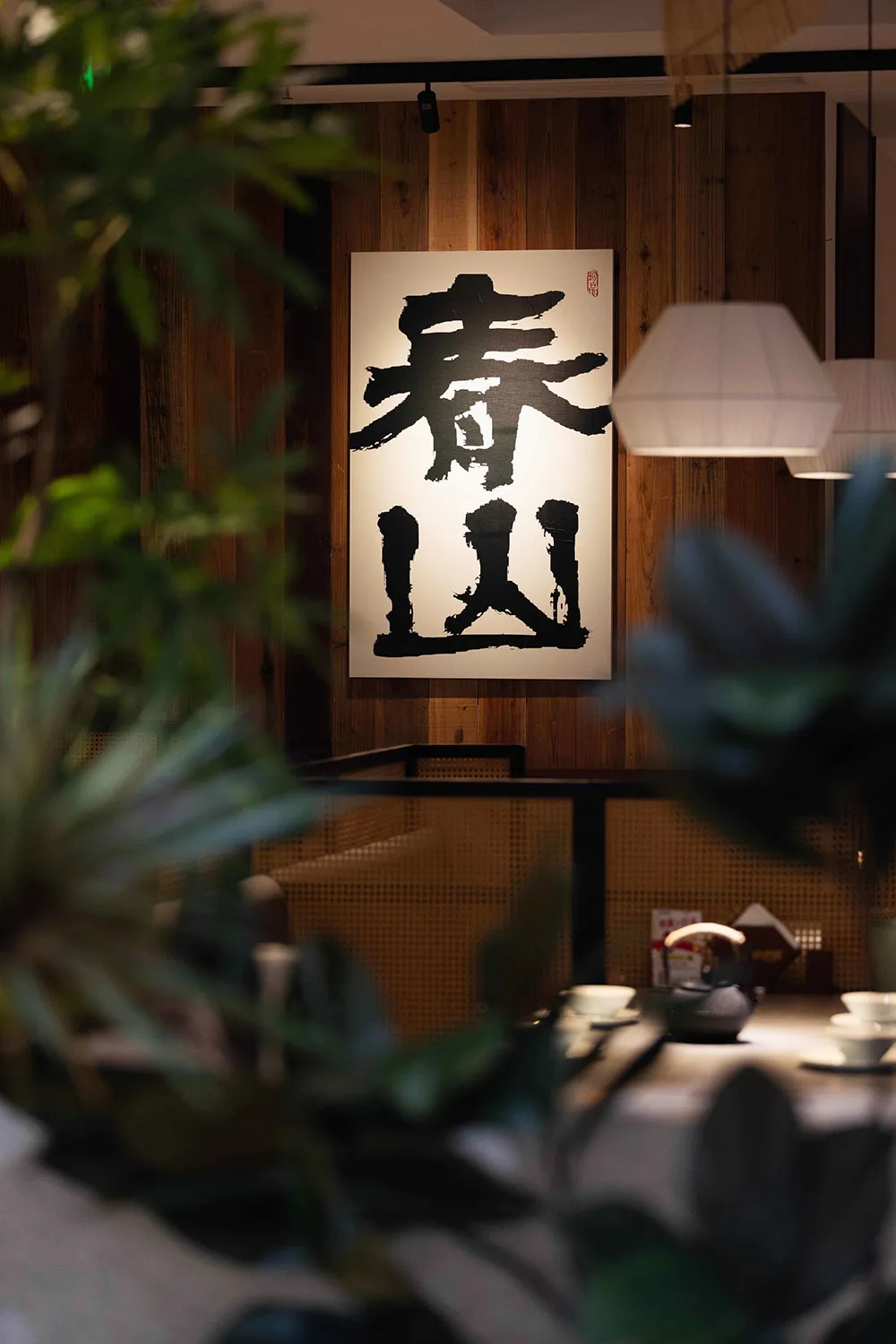 一間舒適的餐廳，餐桌、椅子、花盆和牆上的大型黑白畫作