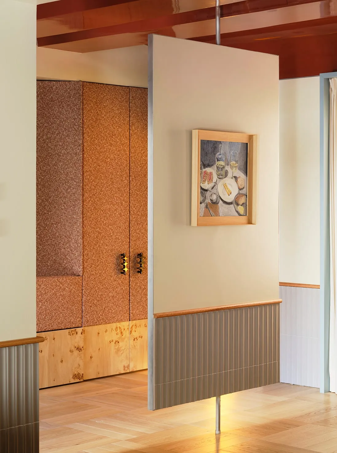 A warm and inviting hallway with a yellow wall, wooden floor, and a painting of a dining table with food on it