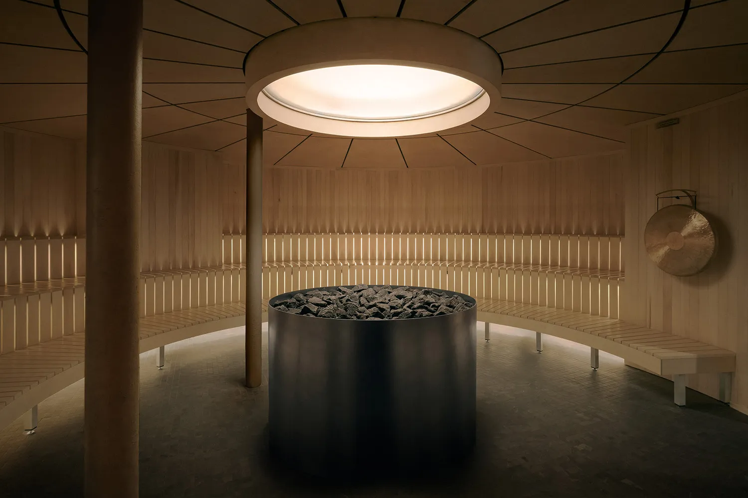A modern lobby with a large metal vase in the center, a wooden floor, and dim lighting creating a calm atmosphere