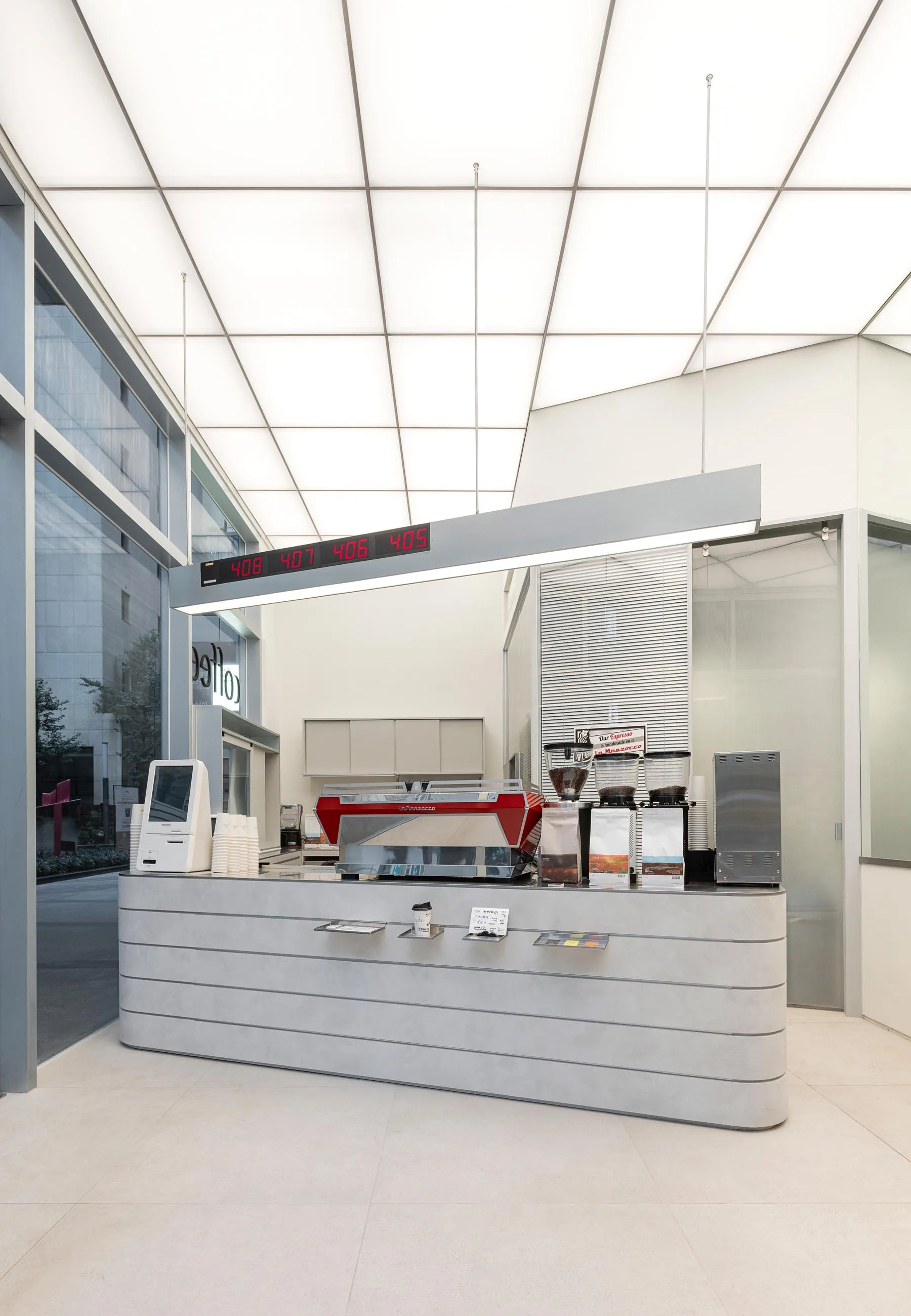 A well-lit coffee shop with a modern design, featuring a counter with coffee beans and cups, and a welcoming atmosphere