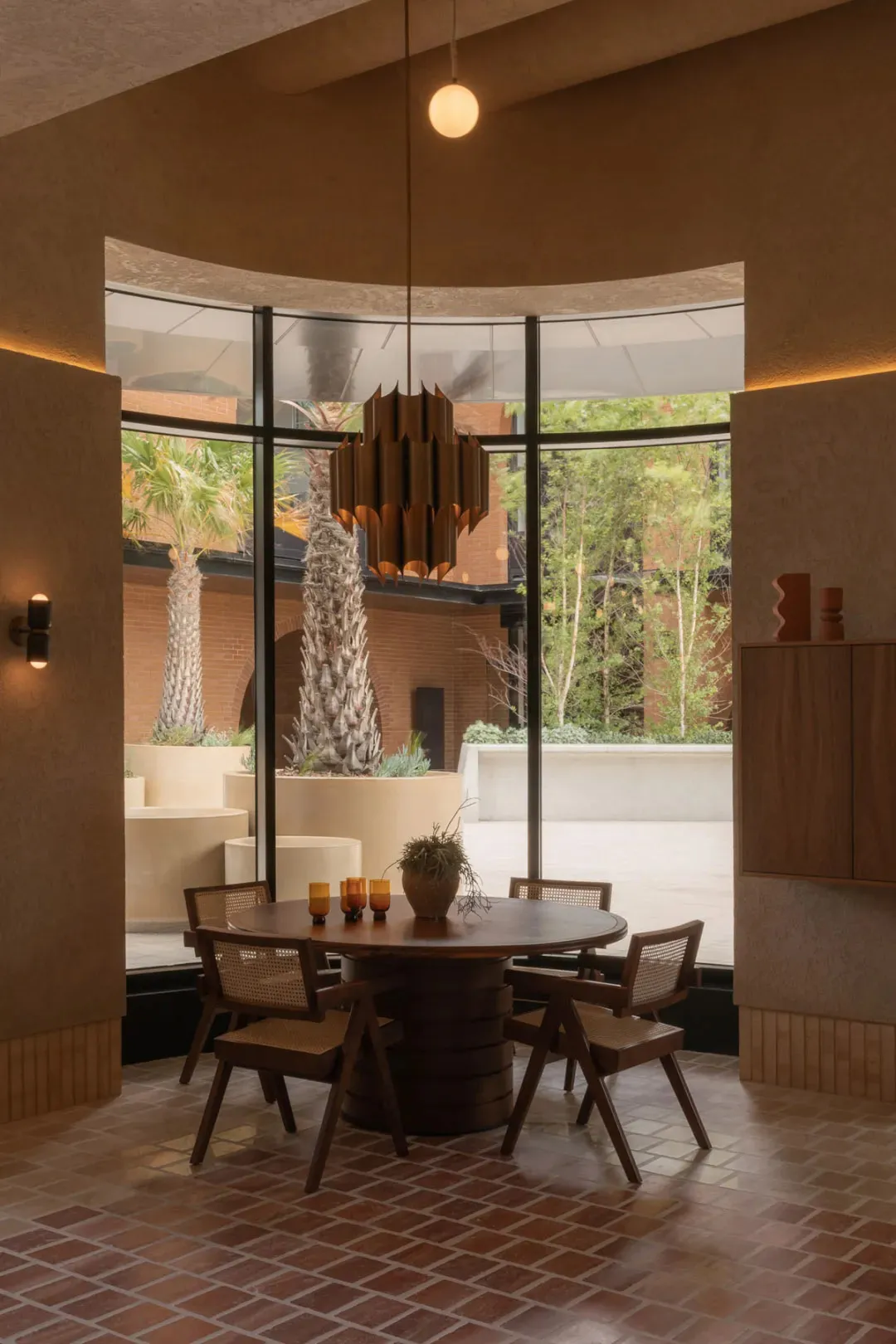 A modern dining room with a table and chairs, surrounded by vases, and a large window allowing natural light to enter