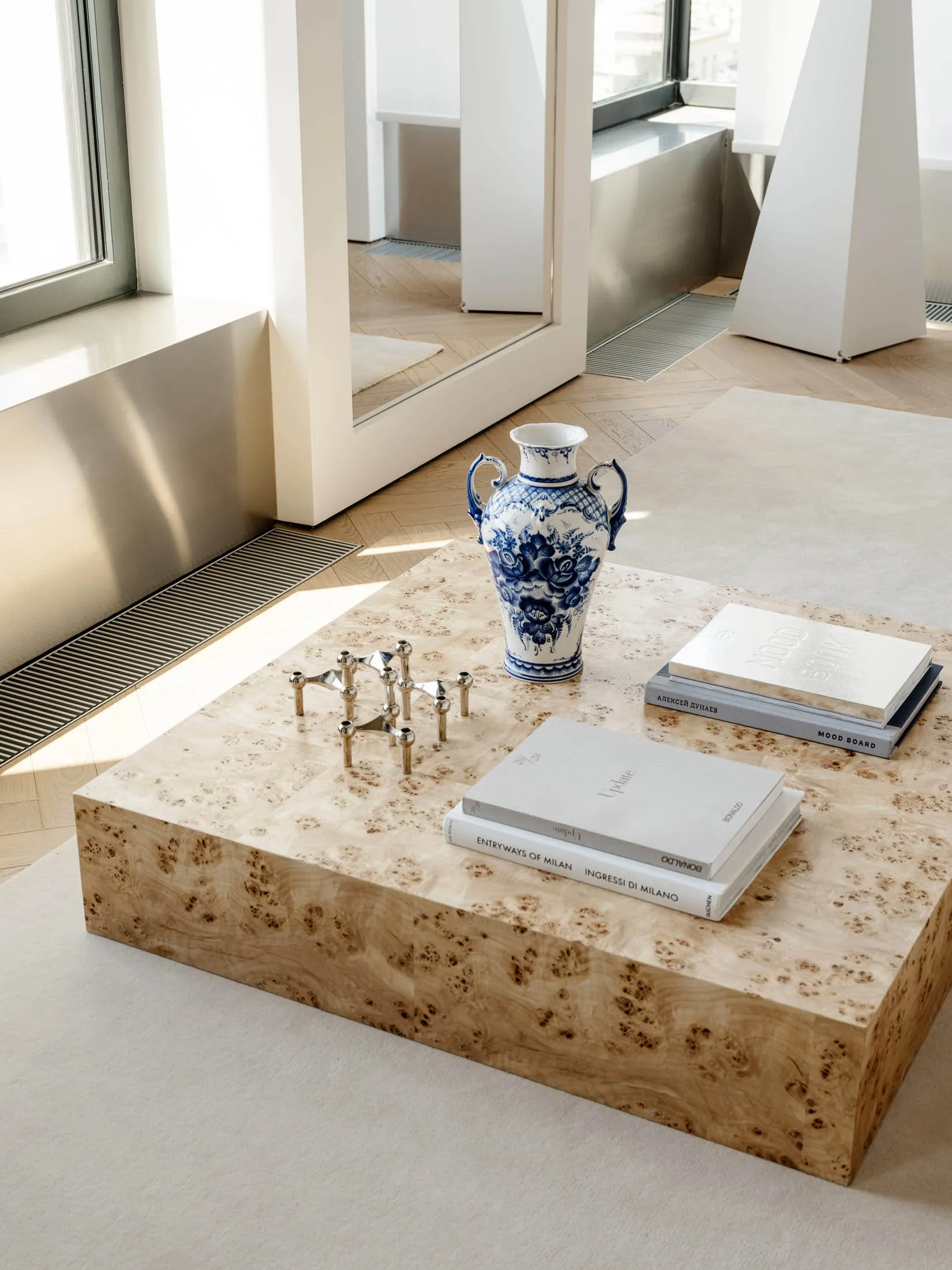 Cozy living room with a wooden coffee table, books, and a vase, featuring a mix of natural and artificial lighting