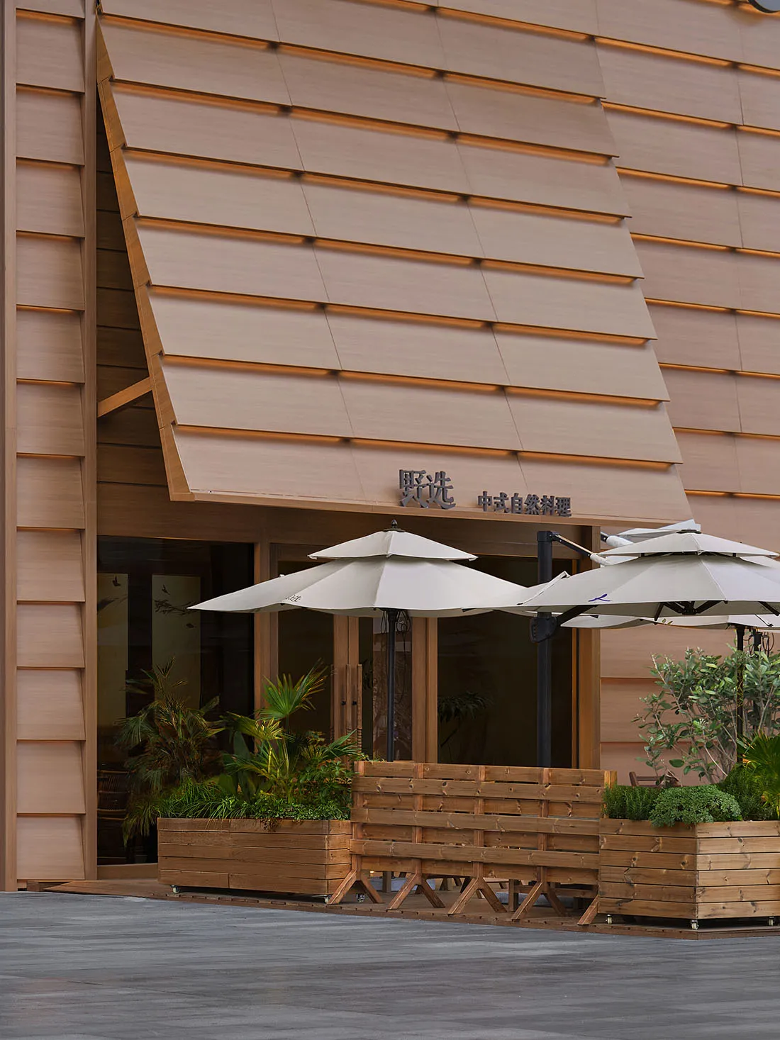 Photograph of a traditional building with a brown wooden exterior, featuring a large wooden awning and a wooden bench in front of it