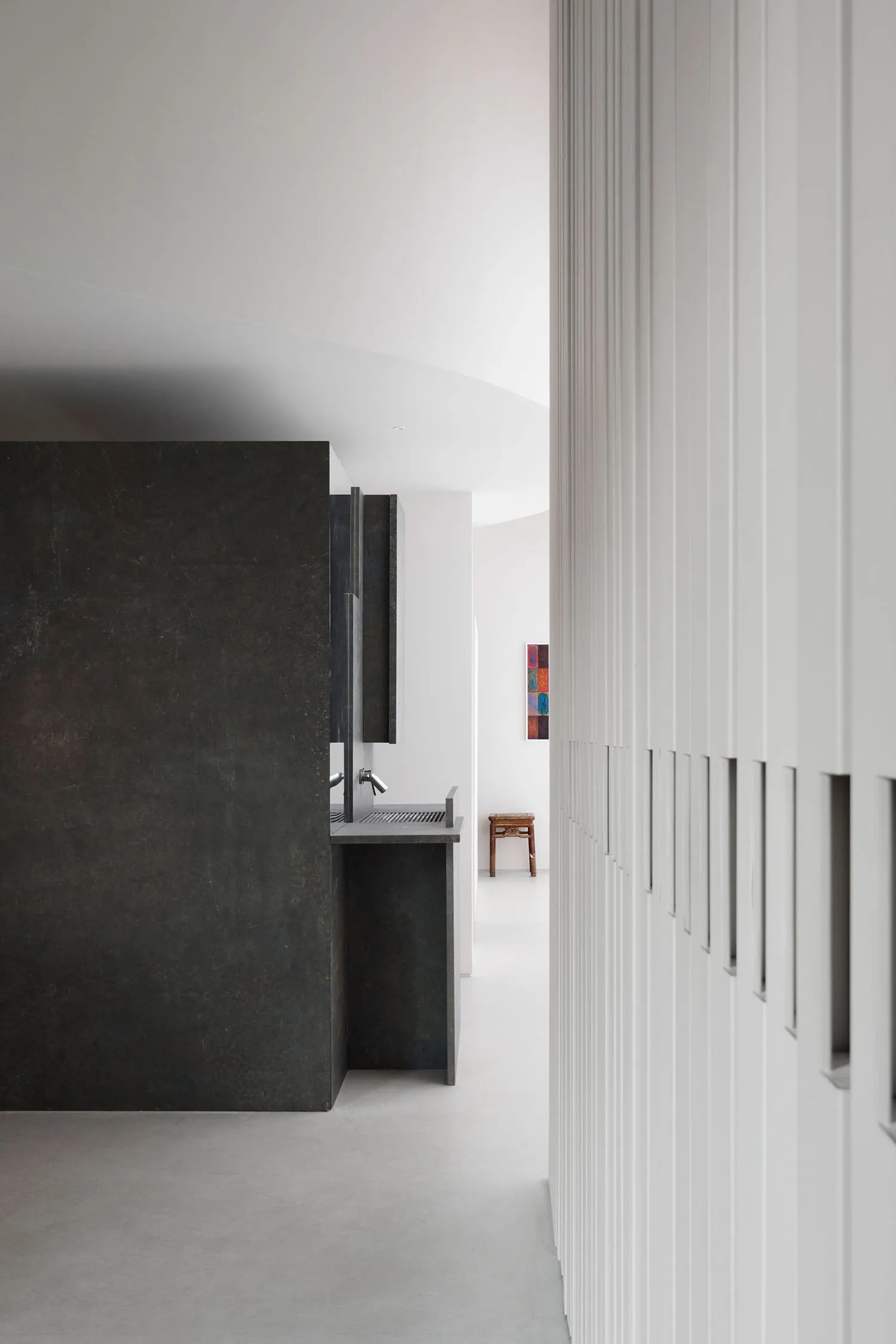 Modern kitchen with a black granite countertop, black cabinets, a sink, and refrigerator in a dimly lit space